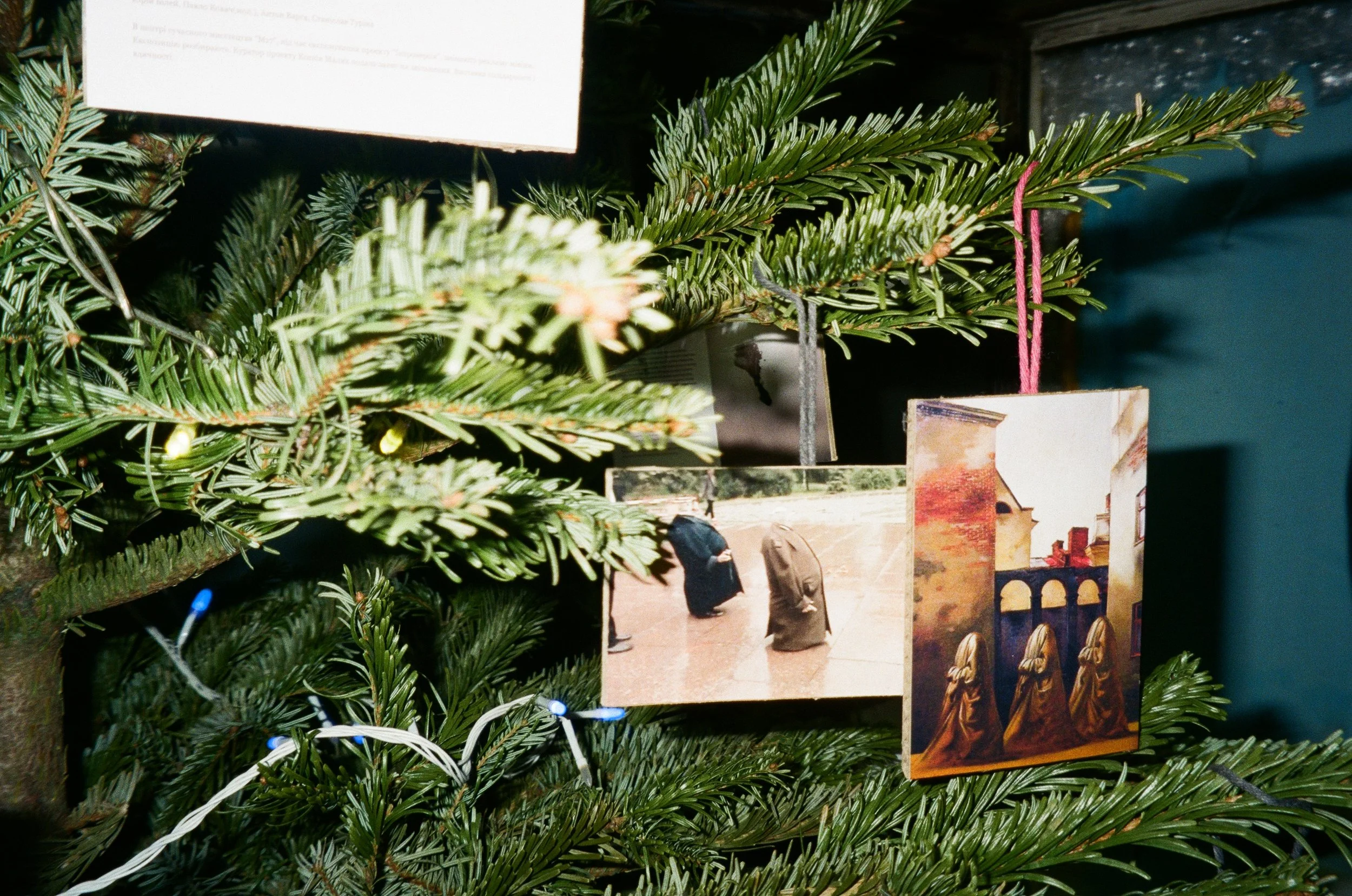 Close-up of a decorated Christmas tree with photo cards and a tag hanging from its branches.