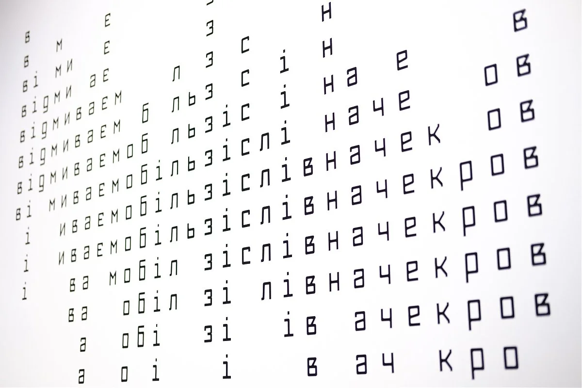 Close-up of an eye chart with lines of text and characters, some appearing to be in Cyrillic script.