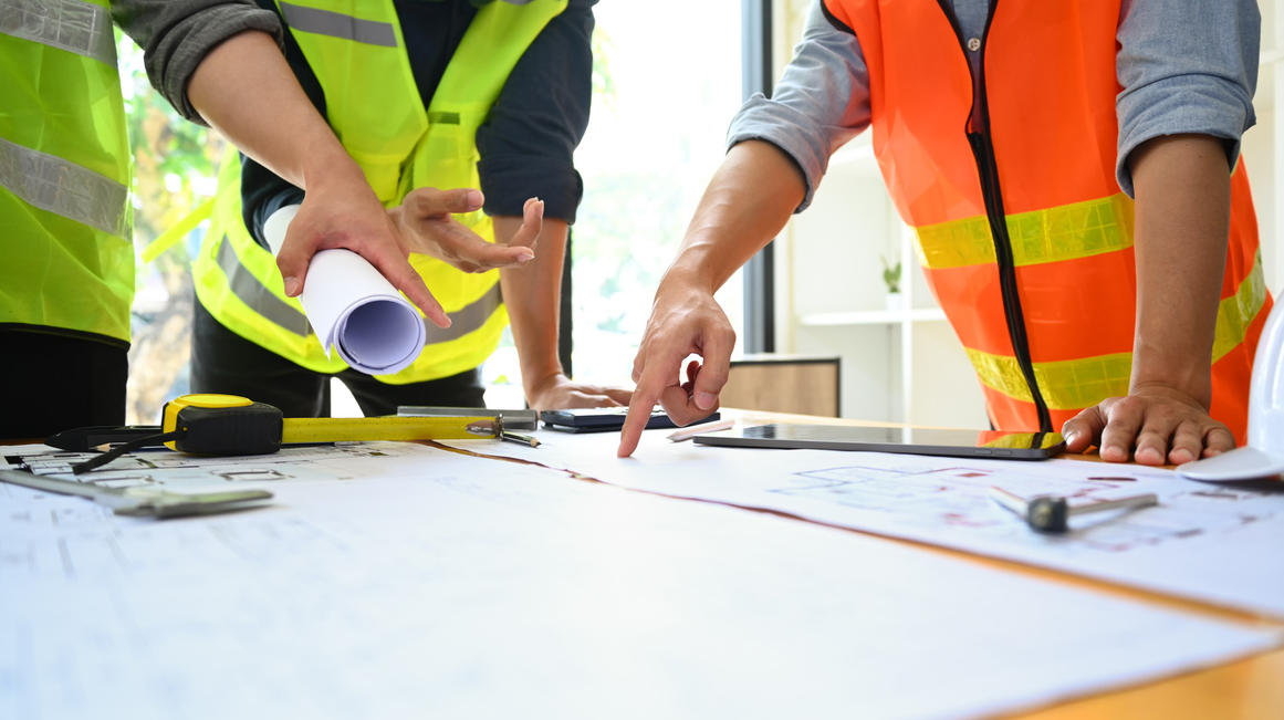 Site workers pointing to plans on a table