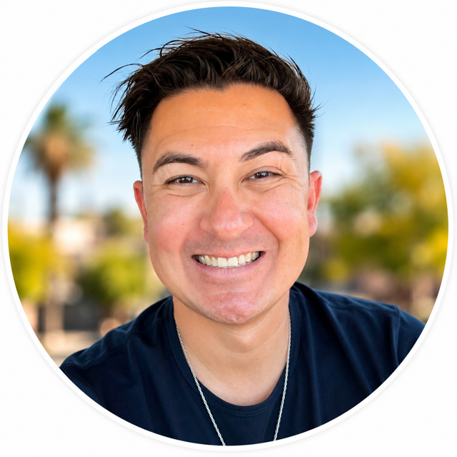 Smiling young man outdoors with blurred trees and blue sky in background