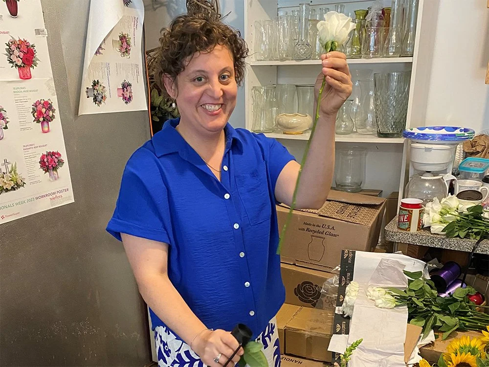 An individual holding a flower and smiling