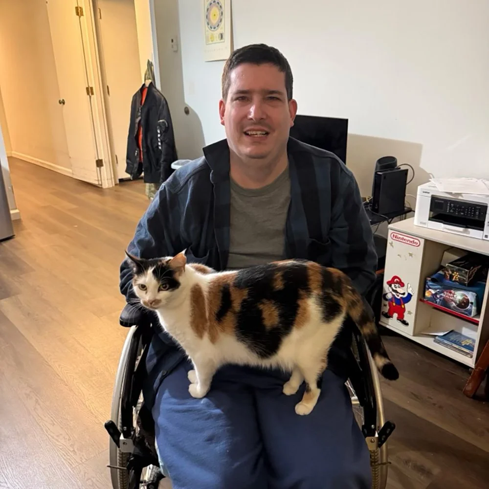 A man at home, with his cat on his lap