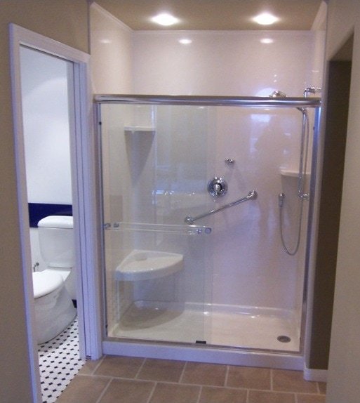 A walk-in shower with glass doors and a handheld showerhead, adjacent to a toilet in a bathroom.