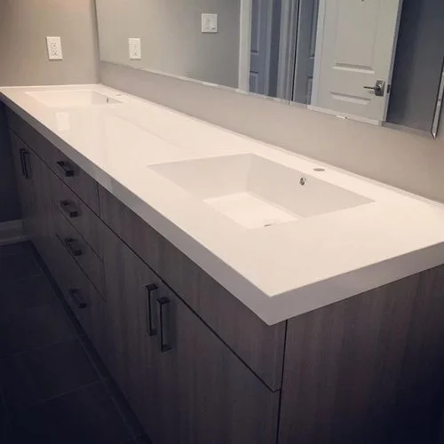 Bathroom vanity with a double sink, large mirror, and wooden cabinet with black handles.