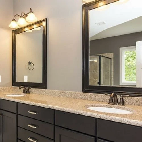 Bathroom vanity with two sinks, granite countertop, black cabinetry, two mirrors, and three-light fixture above each mirror.