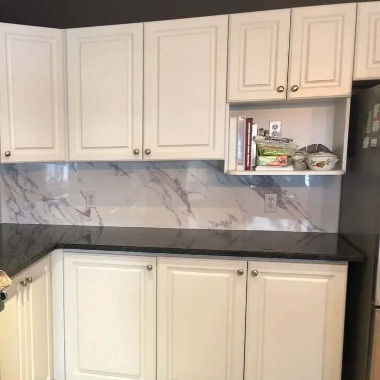 Marble Tradition, bathroom renovation in Kitchener-Waterloo & Cambridge, Ontario. Kitchen with white cabinets, black countertop, marble backsplash, and open shelf with cookbooks and containers.