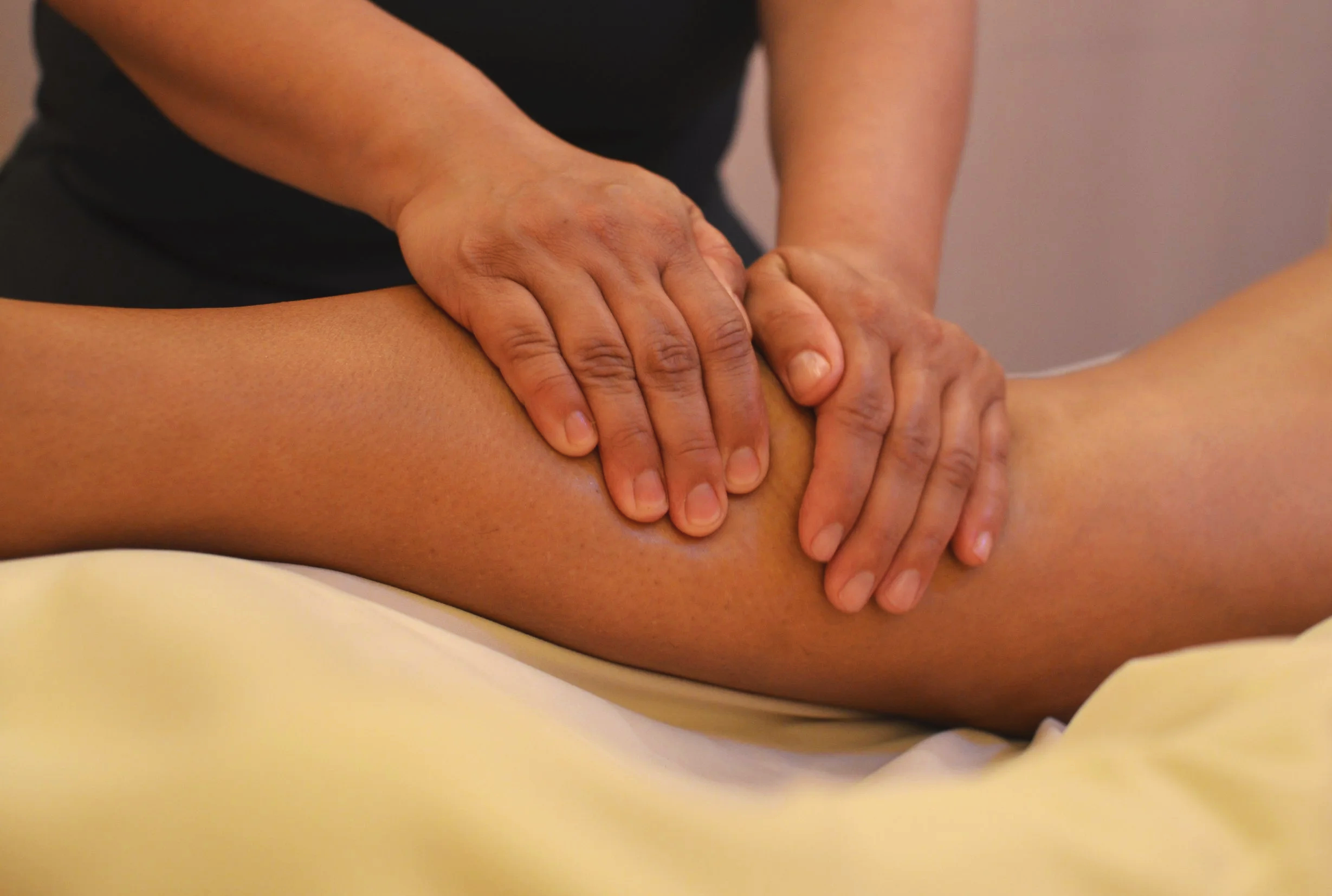 A person giving a massage to another person's leg, focusing on hands pressing into the thigh.