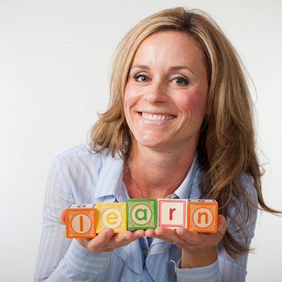 A woman holding colorful baby blocks spelling 'learn'.