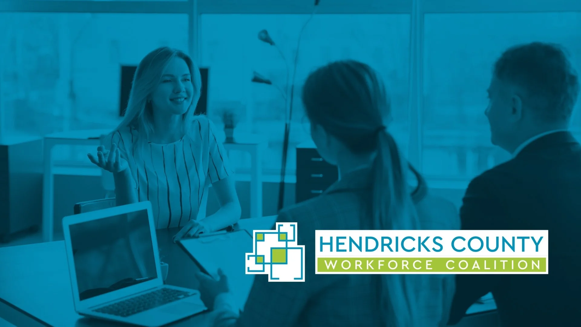 People engaged in a discussion at a meeting table in an office setting, with the Hendricks County Workforce Coalition logo at the bottom.