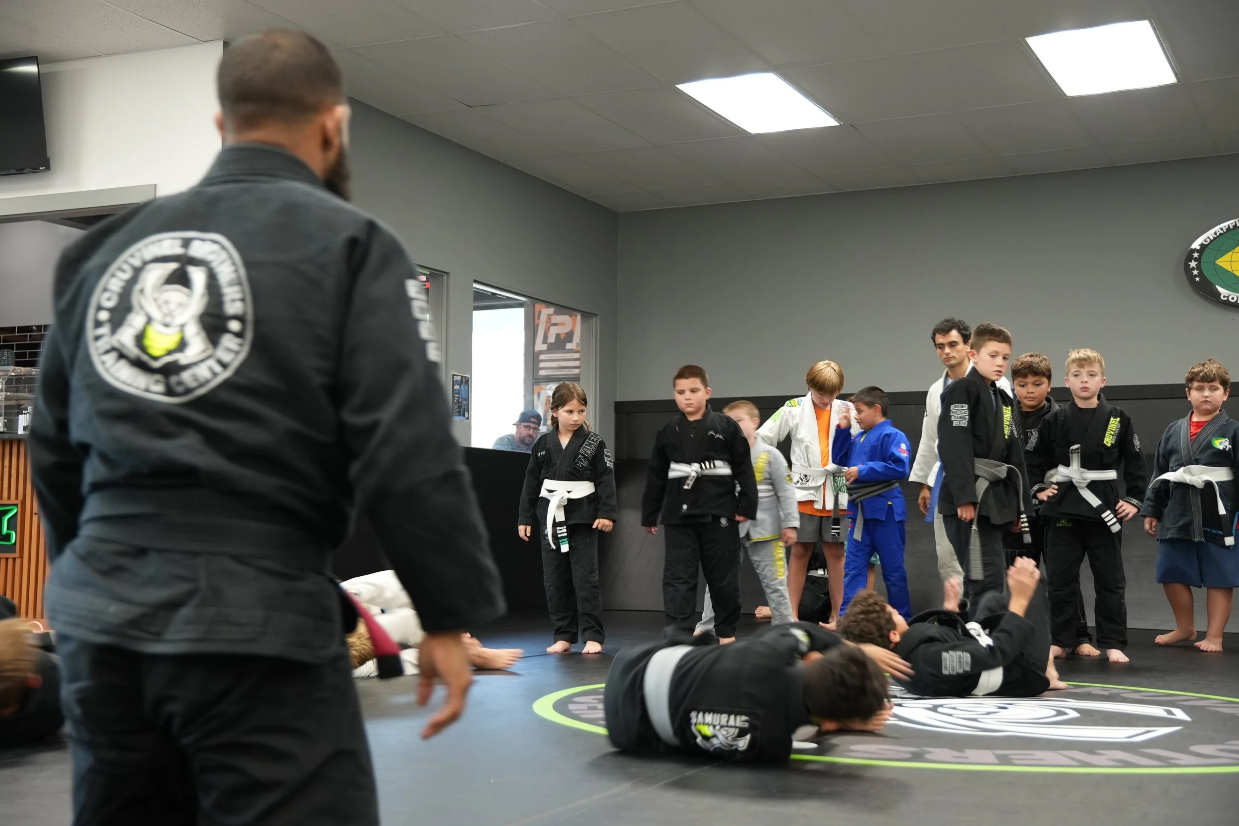 Martial arts class with children and instructors in a training room.