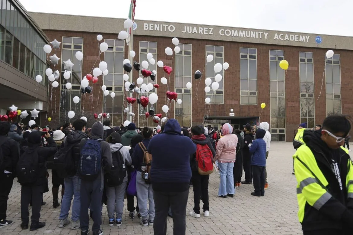 Group of people gathered outside Benito Juarez Community Academy with balloons in the air, some holding signs and taking photos.