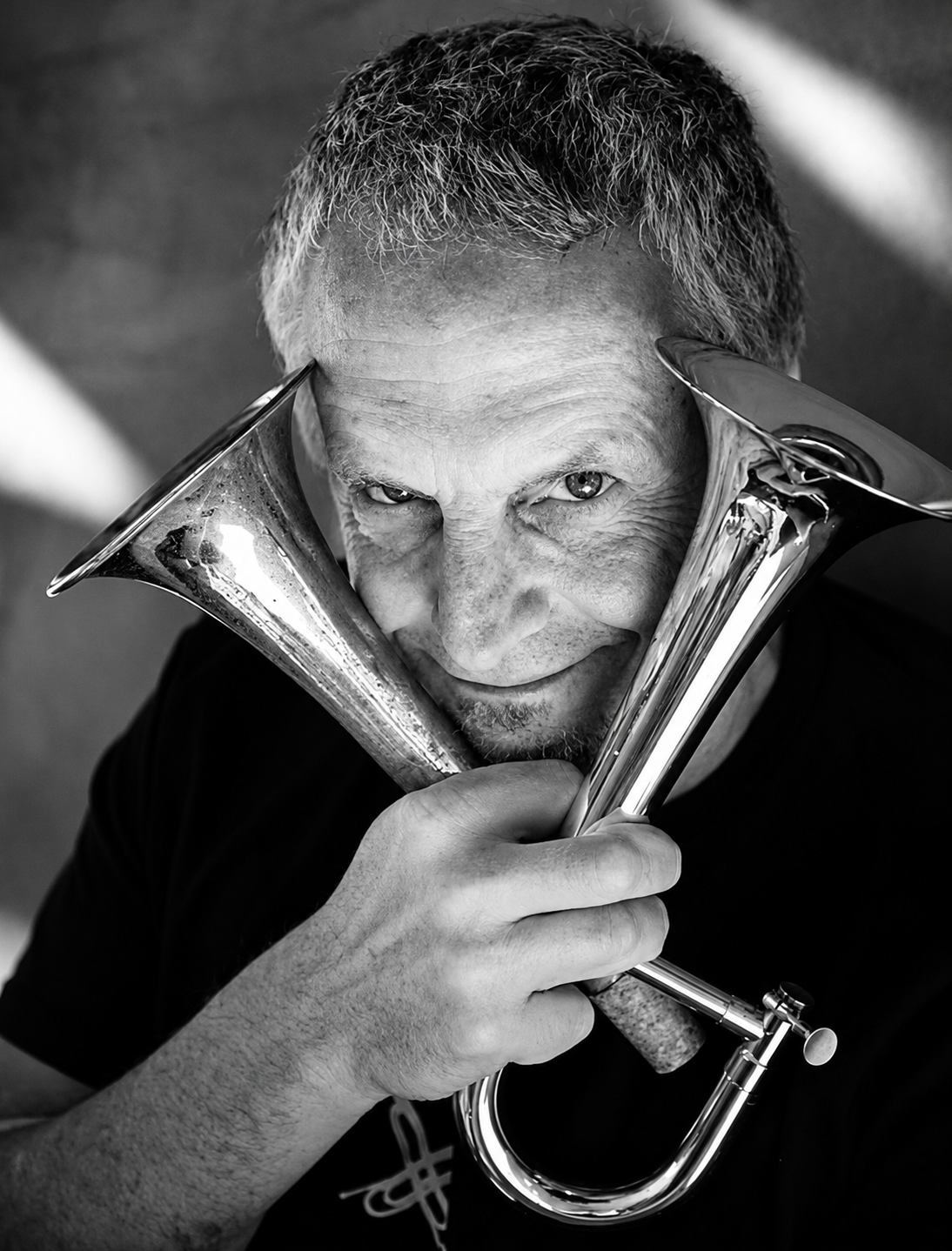 Co-author Richard Gibbs holds two trumpets in cross-formation and grins mischievously at the camera