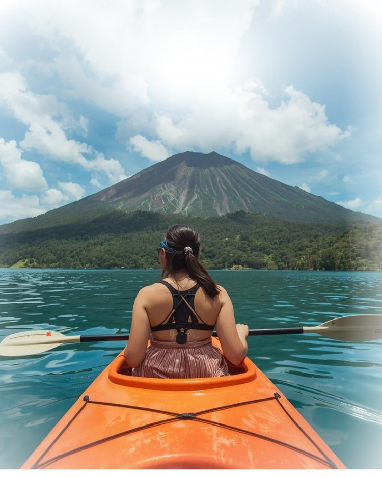 Woman kayaking with volcano in the background