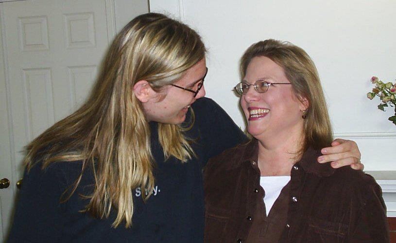 parent and young adult child, smiling at each other. both have blonde hair and glasses