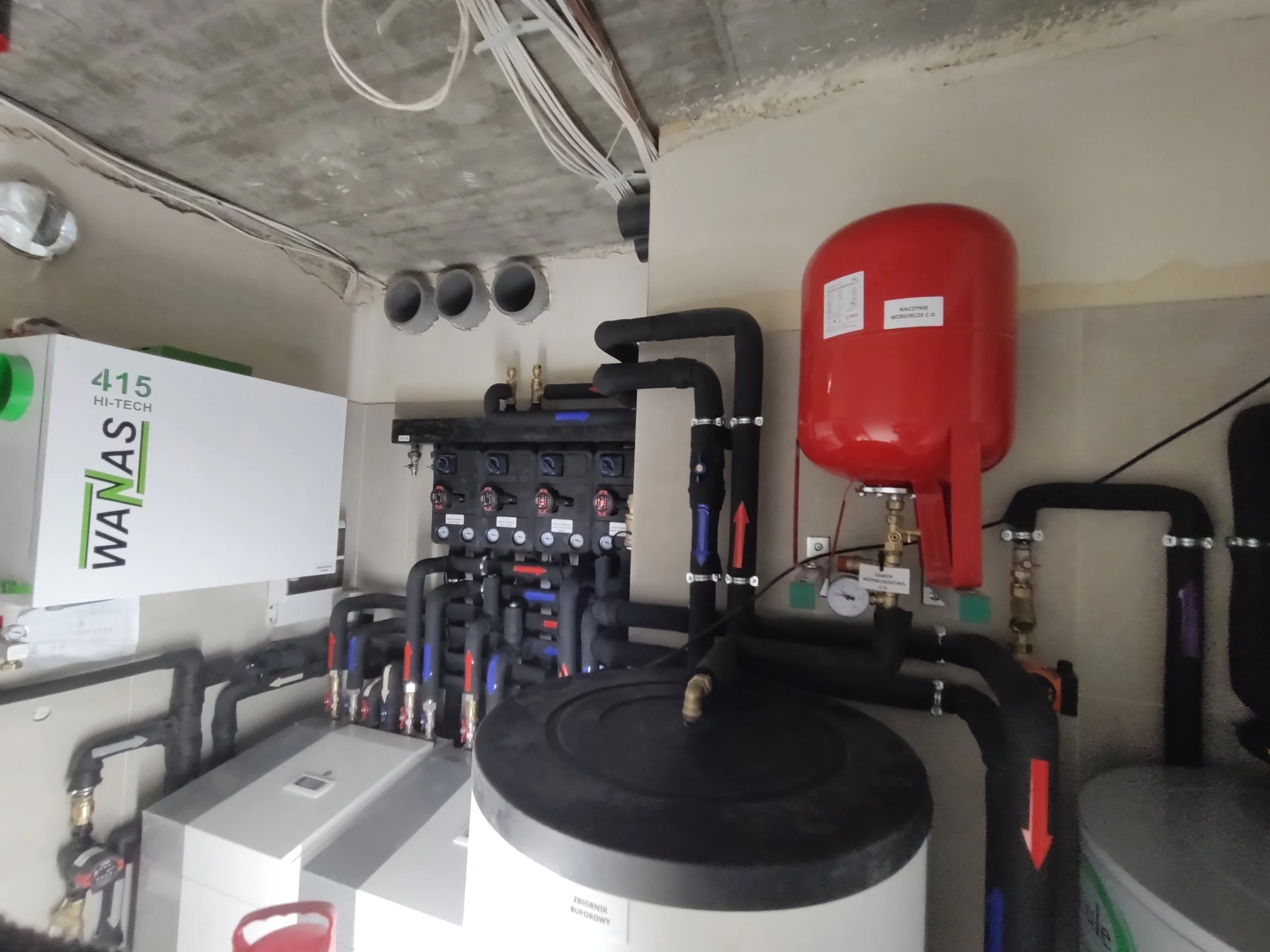 Mechanical room with pipes, meters, and a large red fire suppression tank.