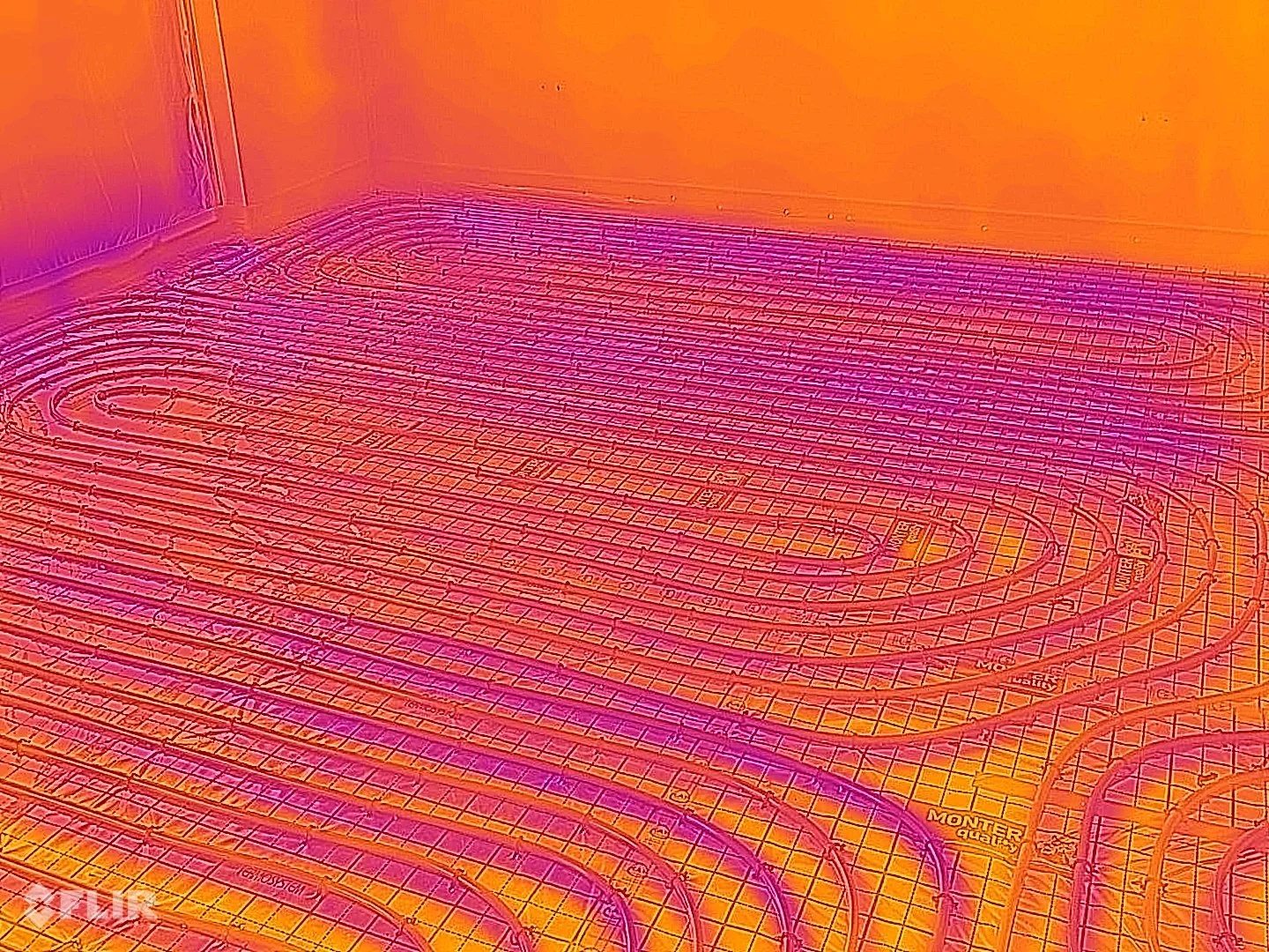 Infrared image of a heated room showing underfloor heating pipes in a floor cavity.