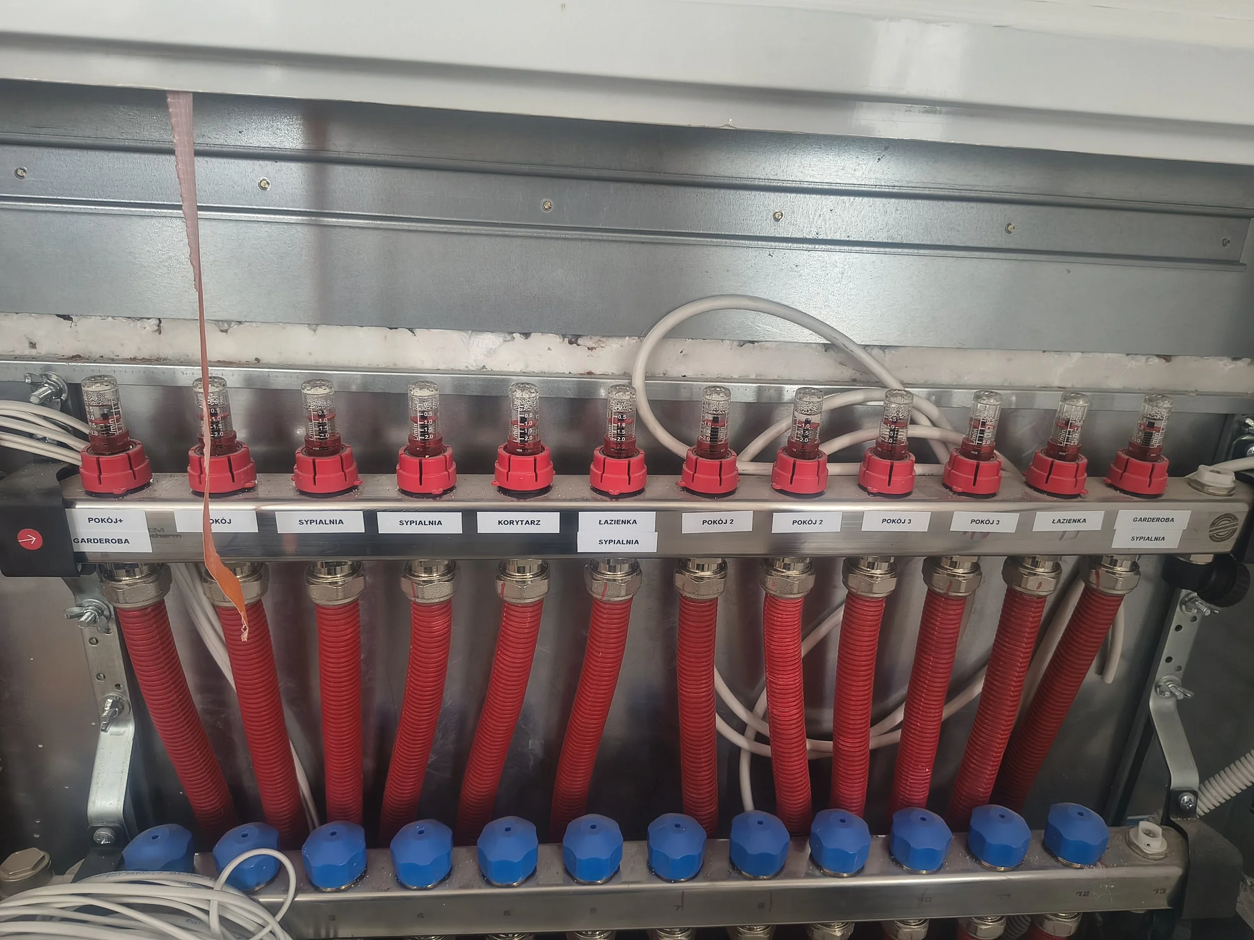Electric control panel with red and blue wiring and labels in Polish, including 'Garderoba' and 'Sypialnia'