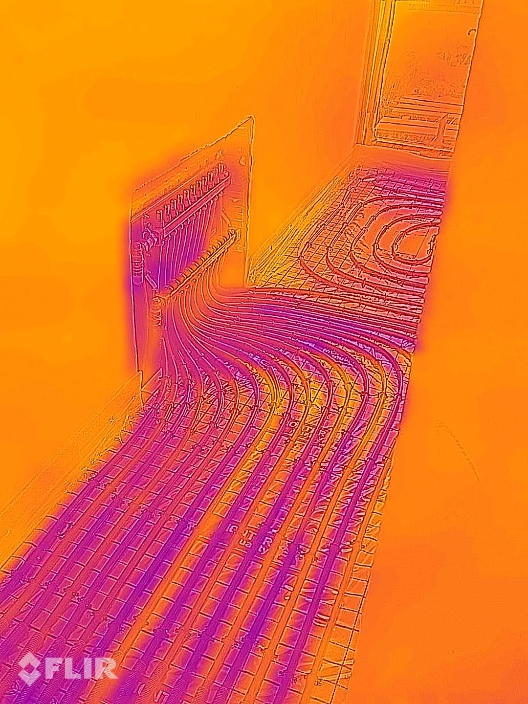 Infrared image of a room with electrical or heating wires along the floor and wall.