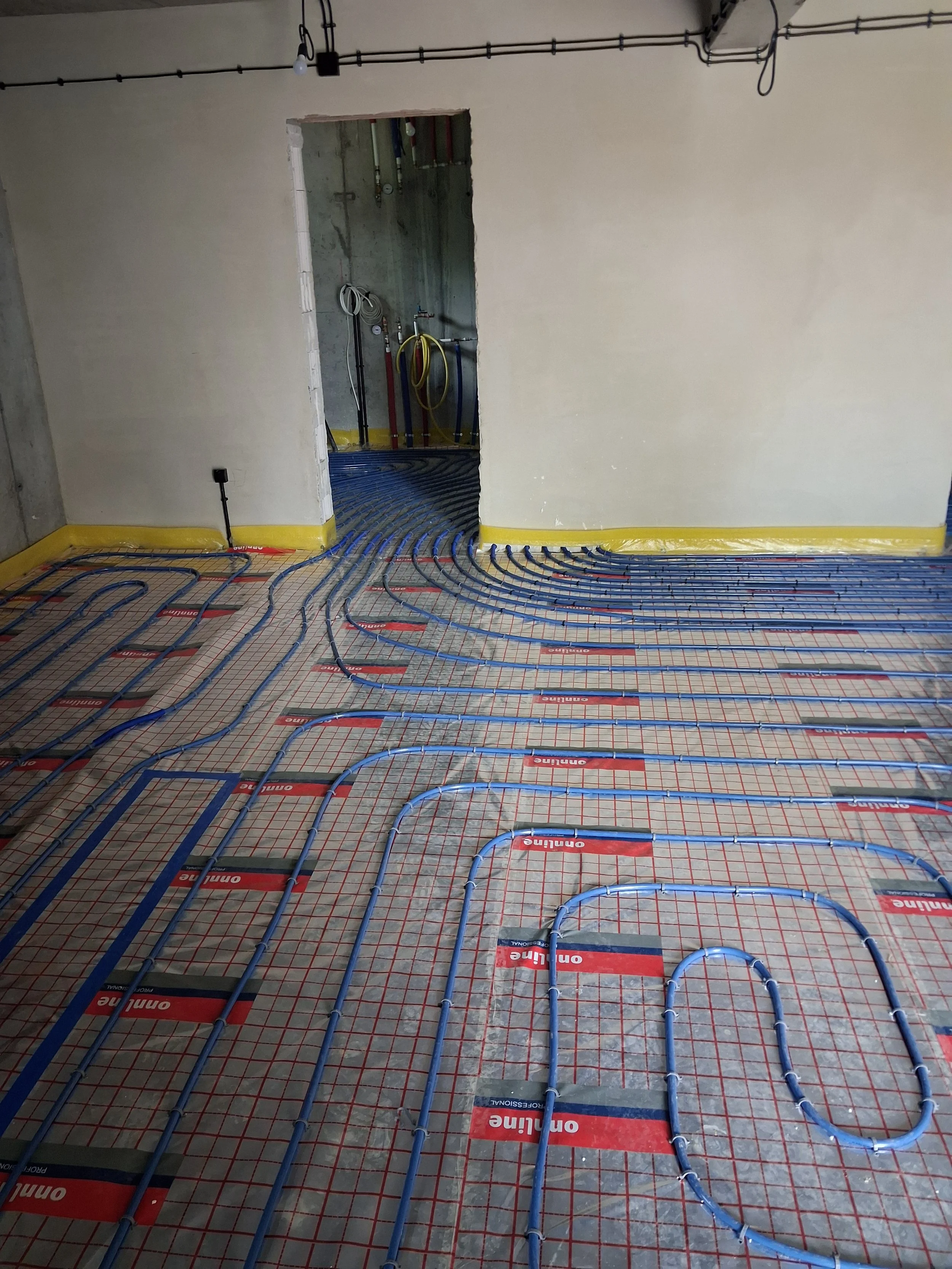 Underfloor heating pipes installed in a building under construction with a concrete subfloor and unfinished walls