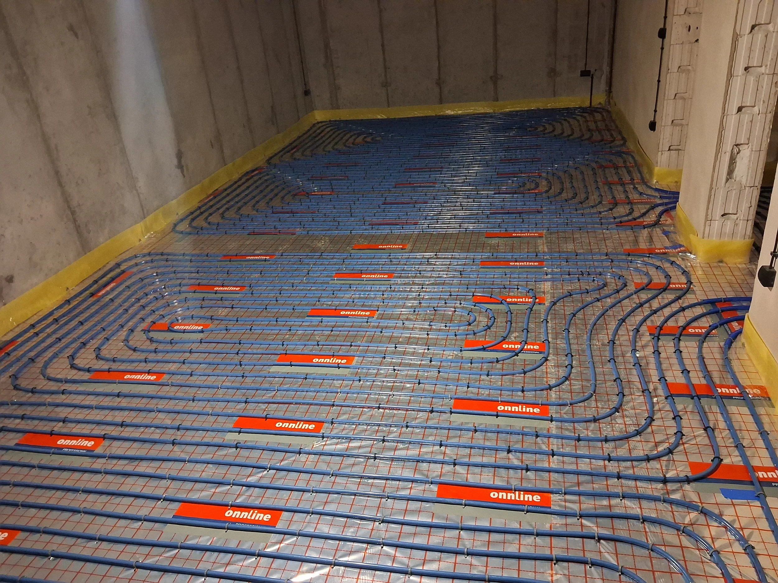 Underfloor heating pipes installed on a concrete floor in a construction site.