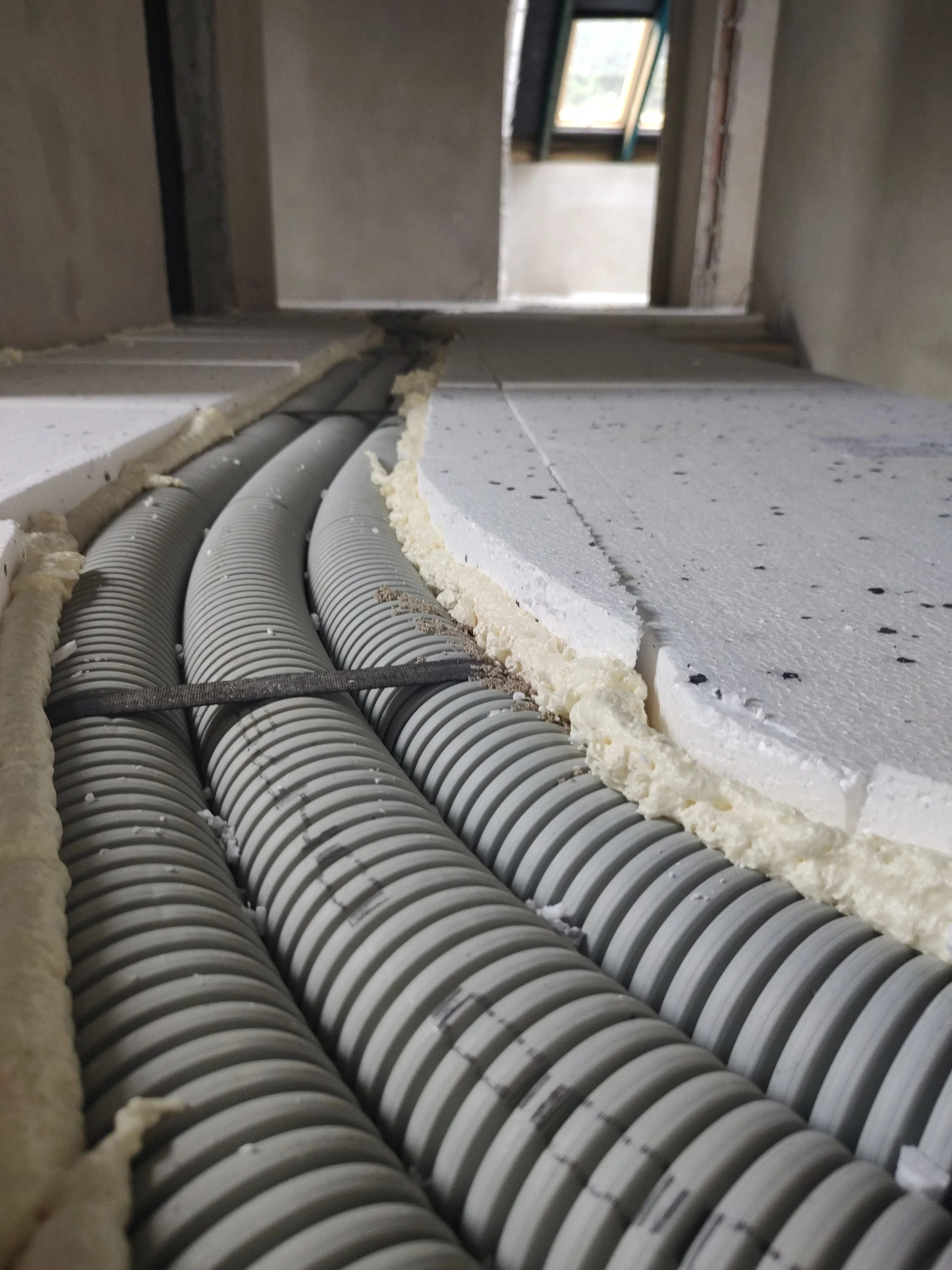 Underground construction site with large gray pipes and spray foam insulation.