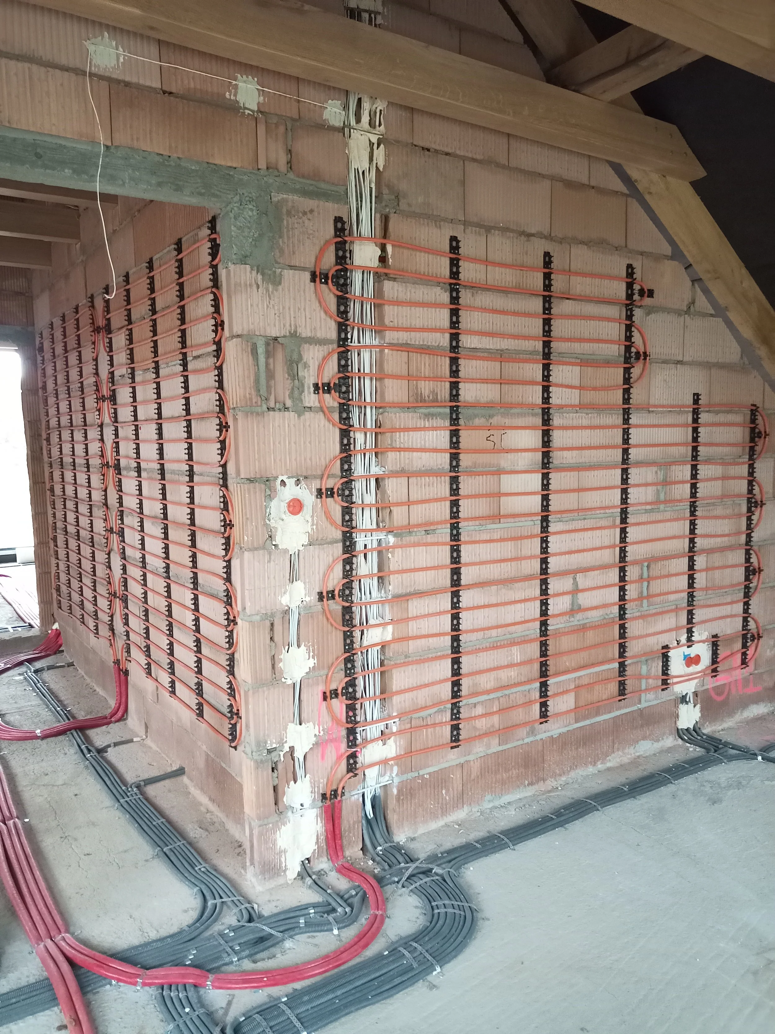 Under-construction wall with embedded electrical wiring, cabling, and pipework in a building.