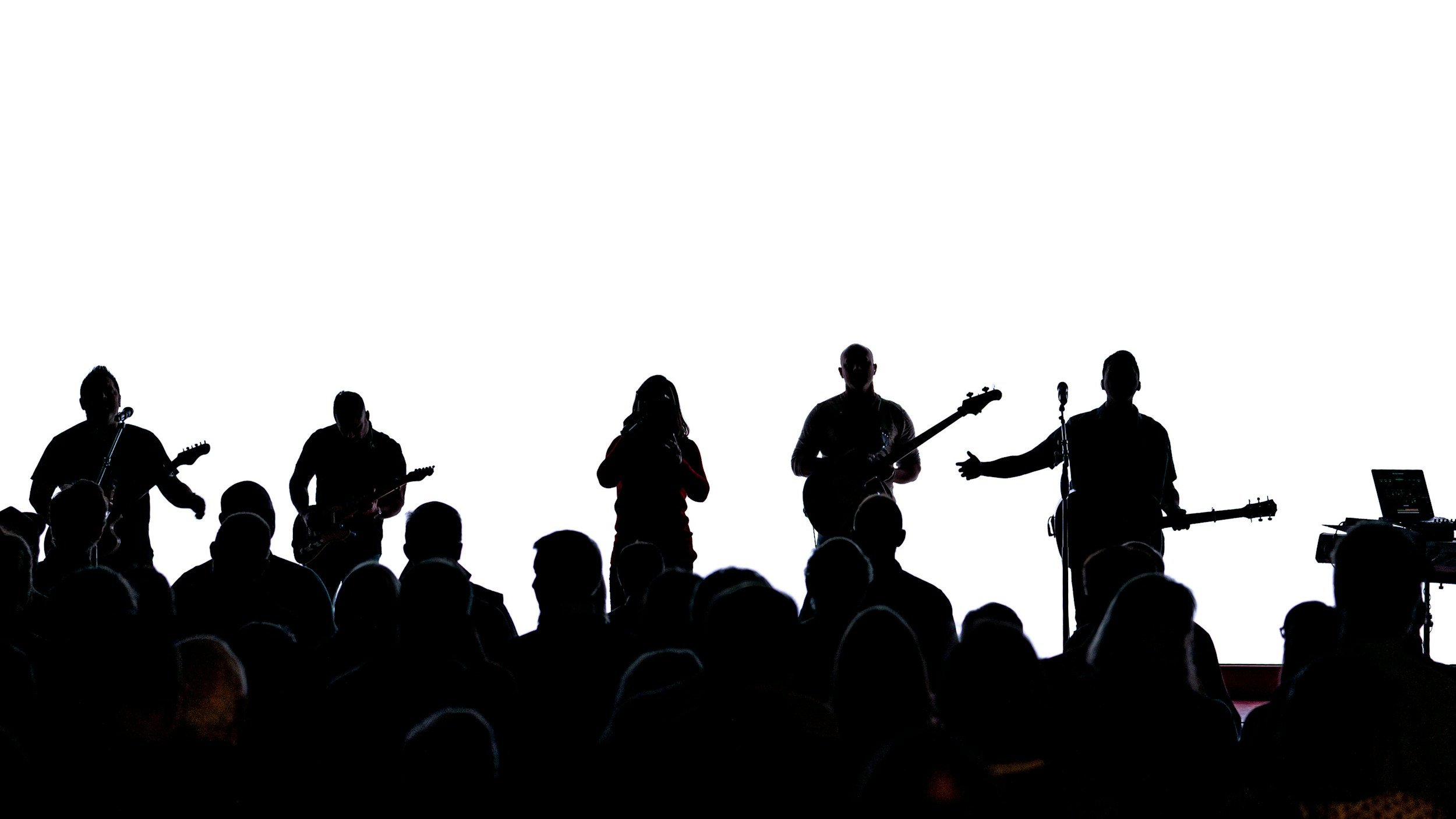 Silhouettes of six musicians performing on stage with a white background, including guitar players, a vocalist, and a keyboardist, with an audience in front.