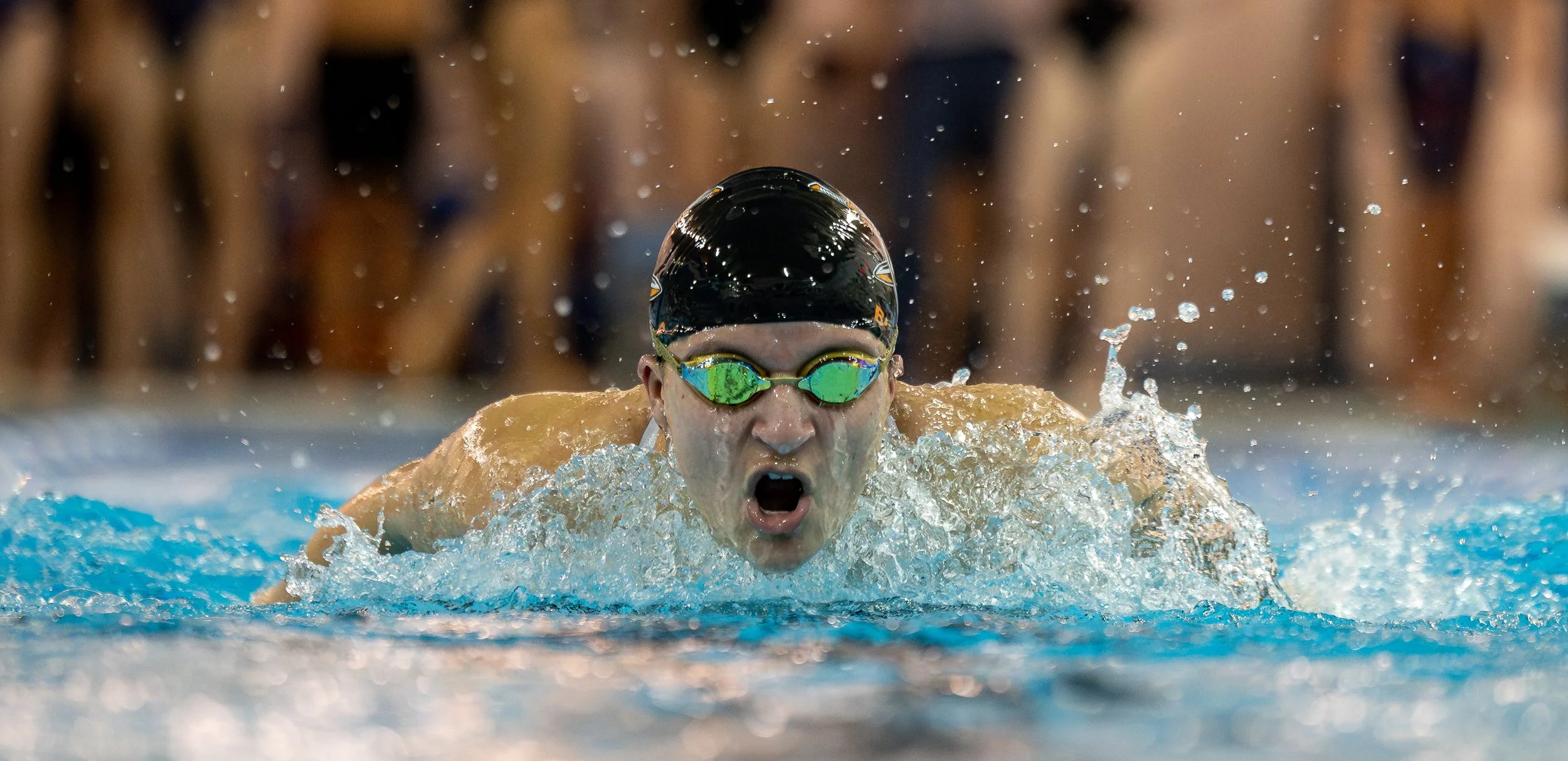 A swimmer in goggles and a swim cap competing in a swimming race.