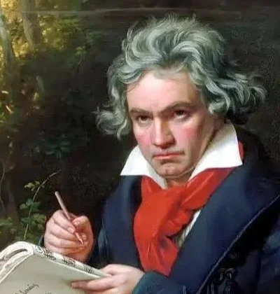 A person dressed as a historical figure with gray, curly hair, wearing a dark coat, white shirt, and red scarf, holding a quill and a notebook outdoors in a wooded area.