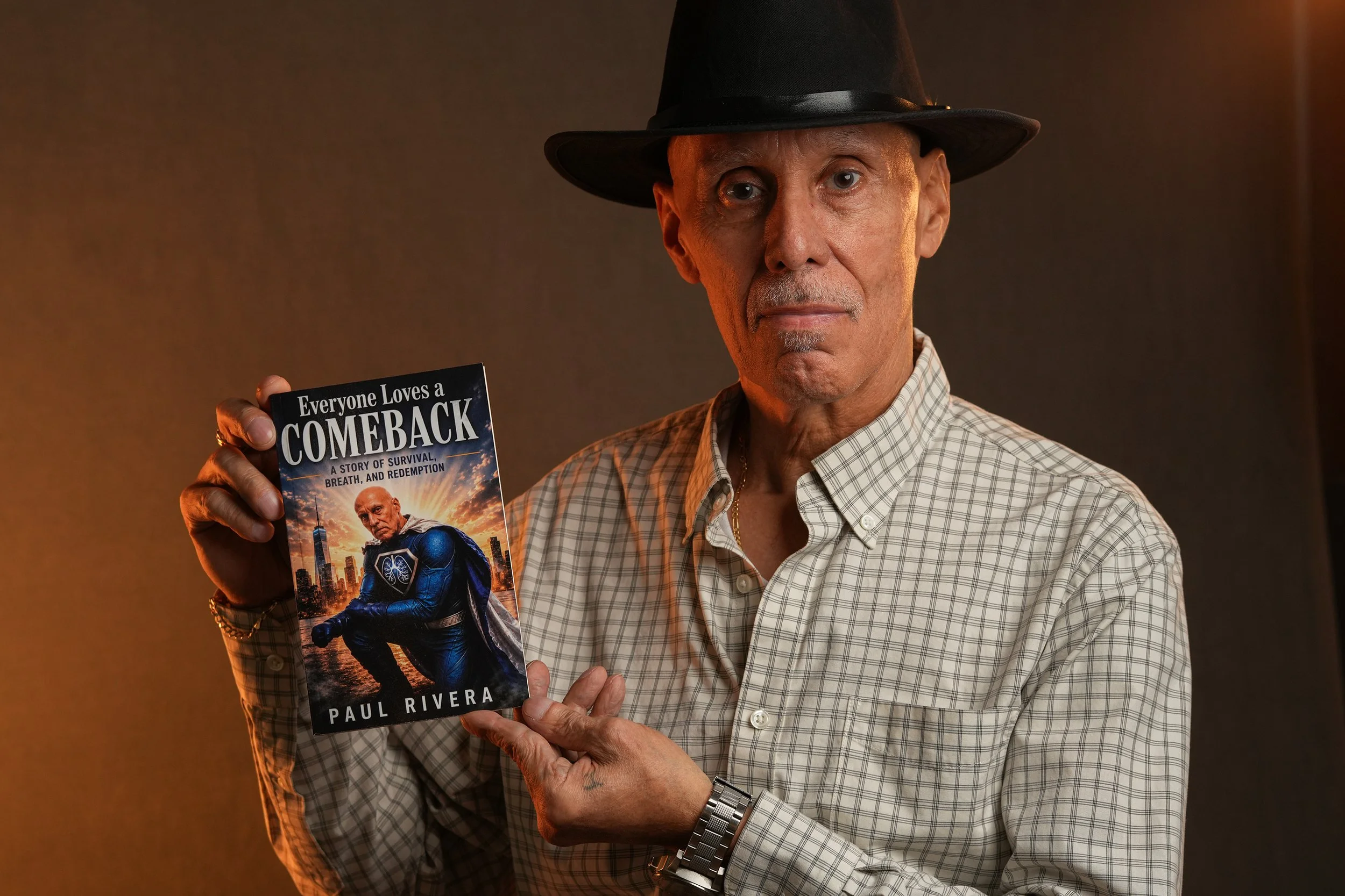 Paul Rivera, author, pointing to his book Everyone Loves a Comeback, cover shows him as a superhero