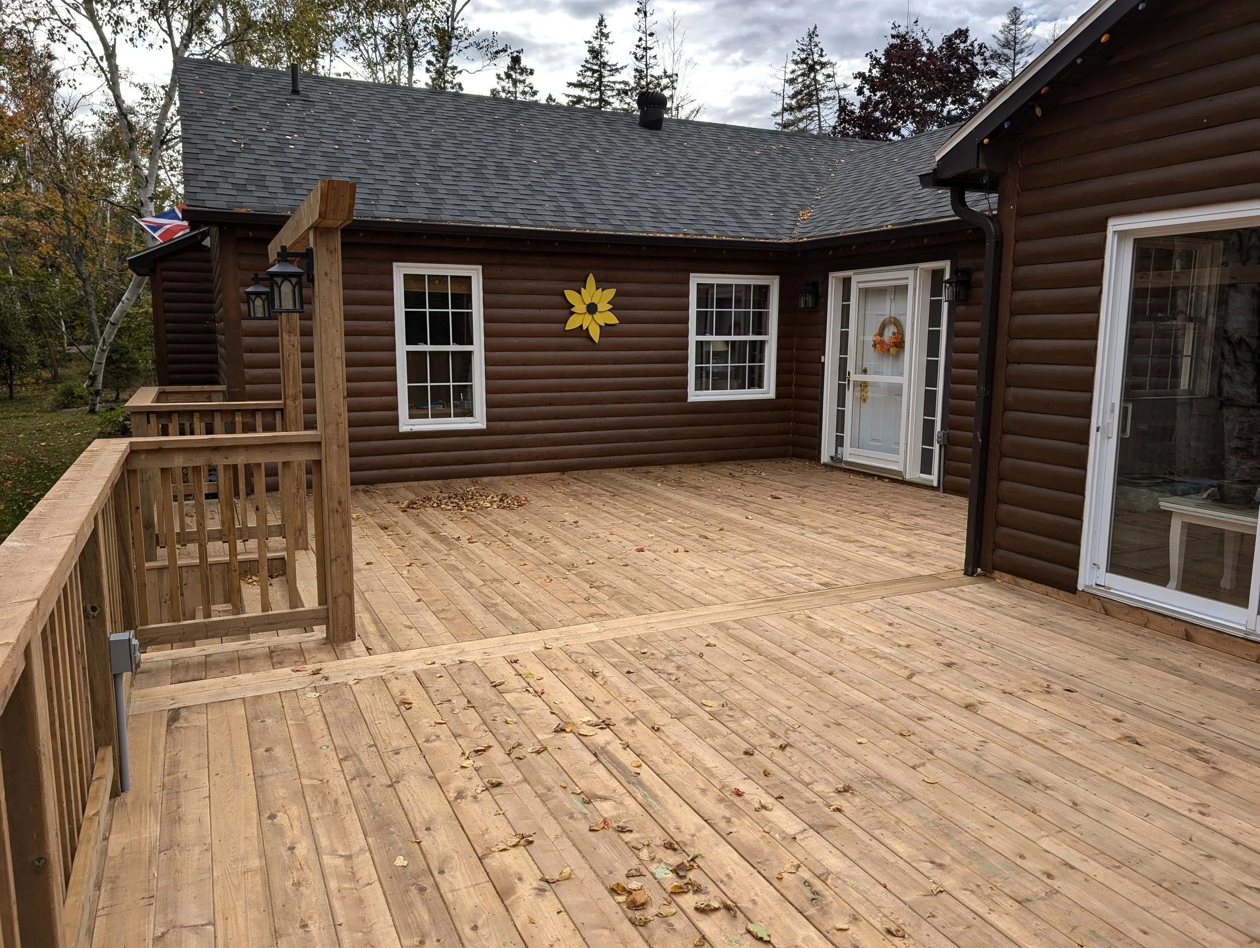 Custom built, pressure treated, multi-level wooden deck with wood railings, and inset step, built for a homeowner in Hunter River, PEI.