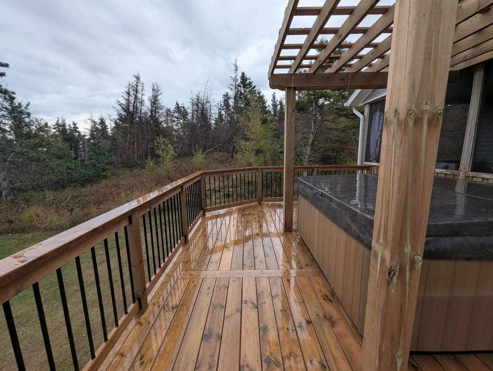 Custom built, pressure treated wood multi-level deck with pergola over the hot tub overlooking the shores of PEI, black aluminum railings, built for a home owner in West Covehead, PEI
