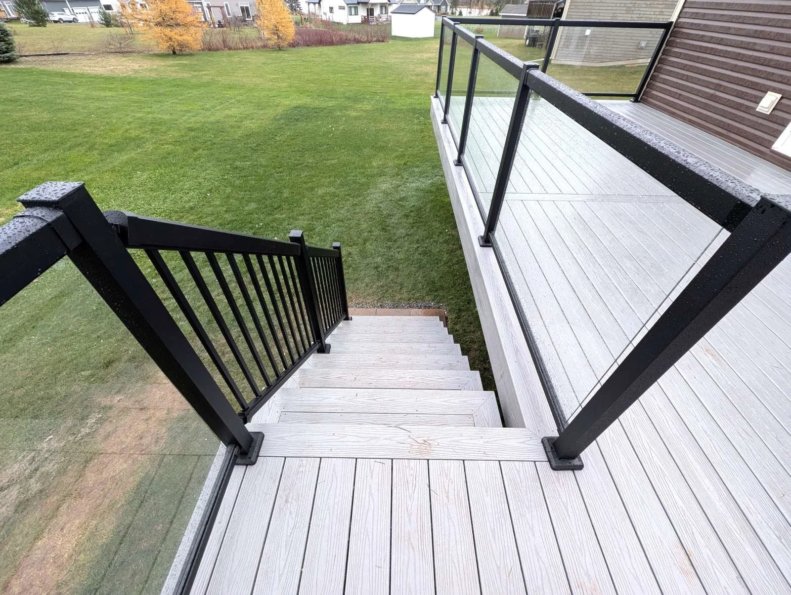 Grey composite deck with glass and black aluminum railings, gazebo and privacy walls for hot tub enclosure built for a homeowner in Cornwall, PEI