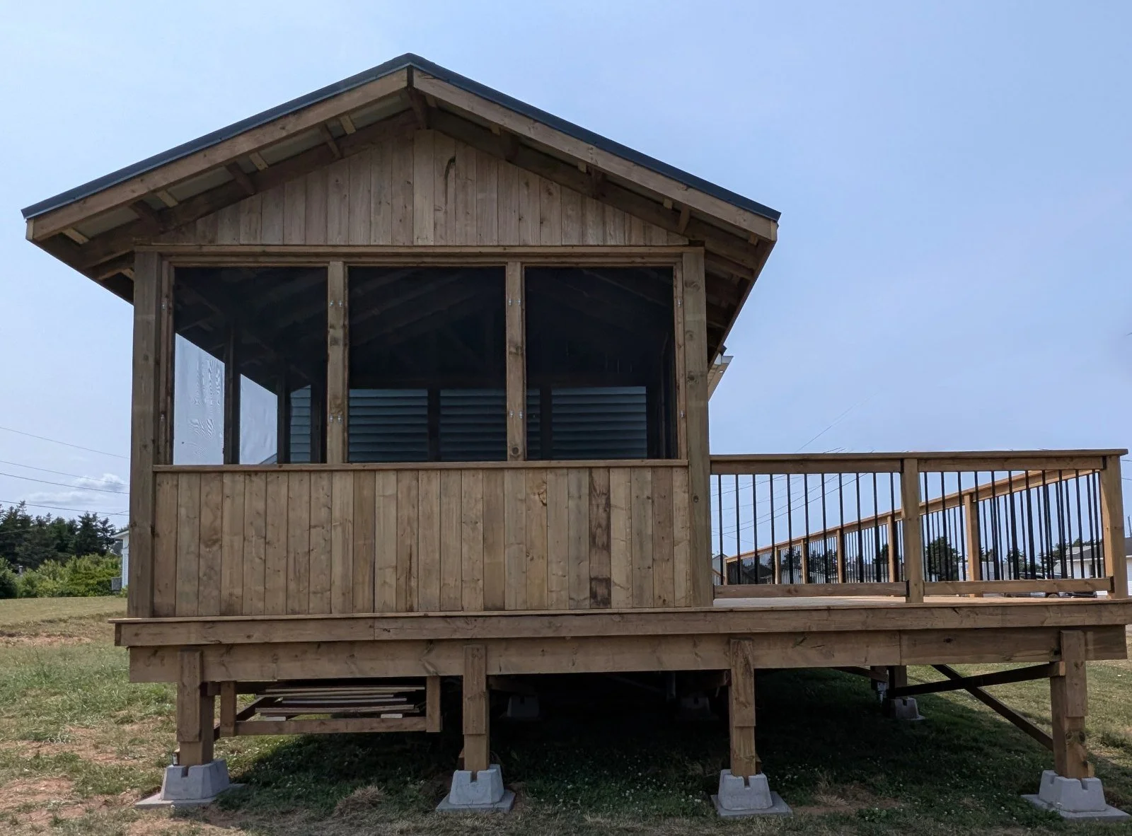 Custom built, pressure treated, wooden deck with a screened-in gazebo on wrap-around deck, and black aluminum railings,  built for a home owner in Wild Harbour, PEI 