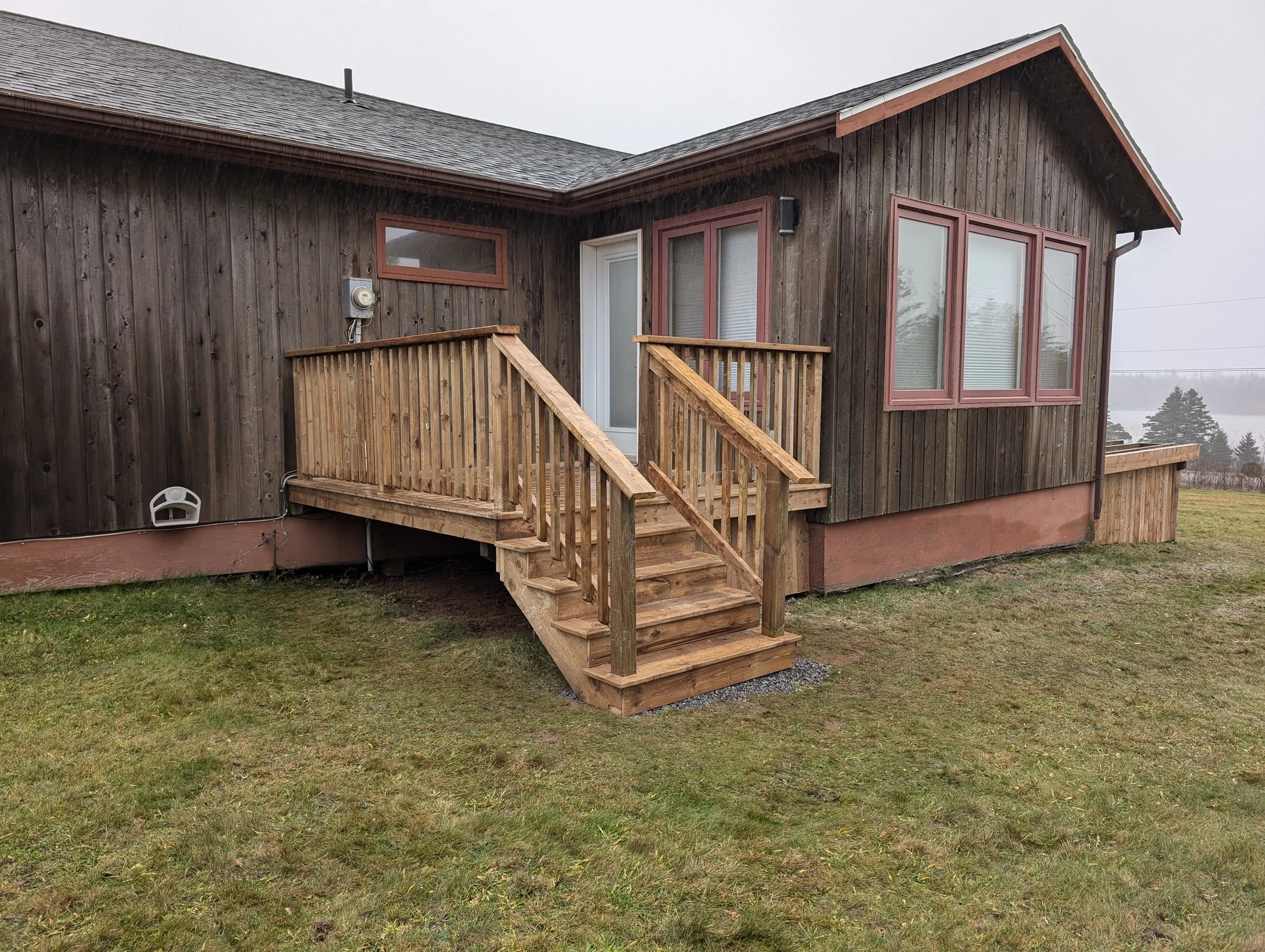 Custom built, pressure treated wooden deck with wood railings and stairs, built for a cottage owner in Stanley Bridge, PEI