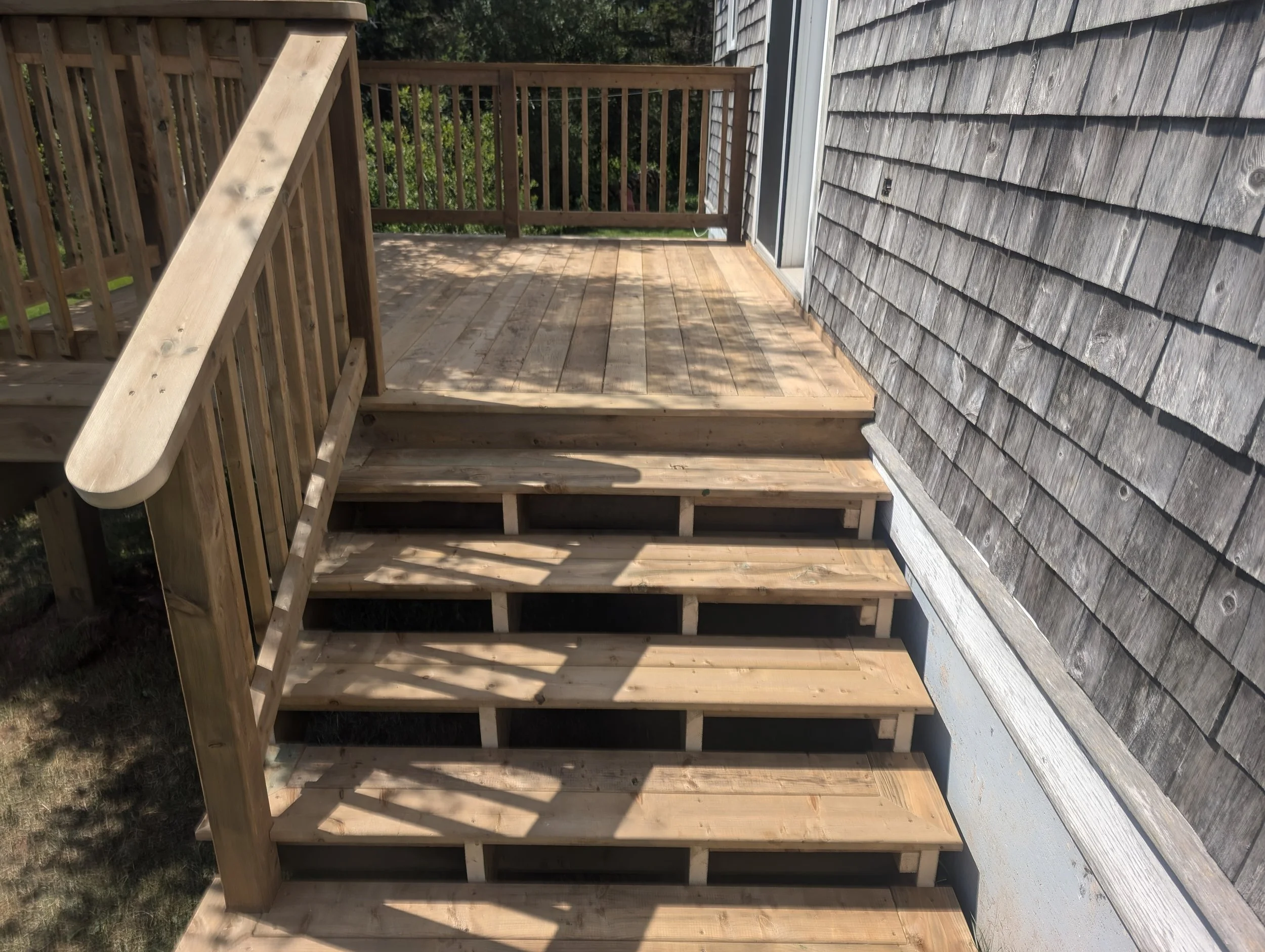 Custom design and built, pressure treated, wooden deck with stairs and wood railing built for homeowner in Stanley Bridge, PEI
