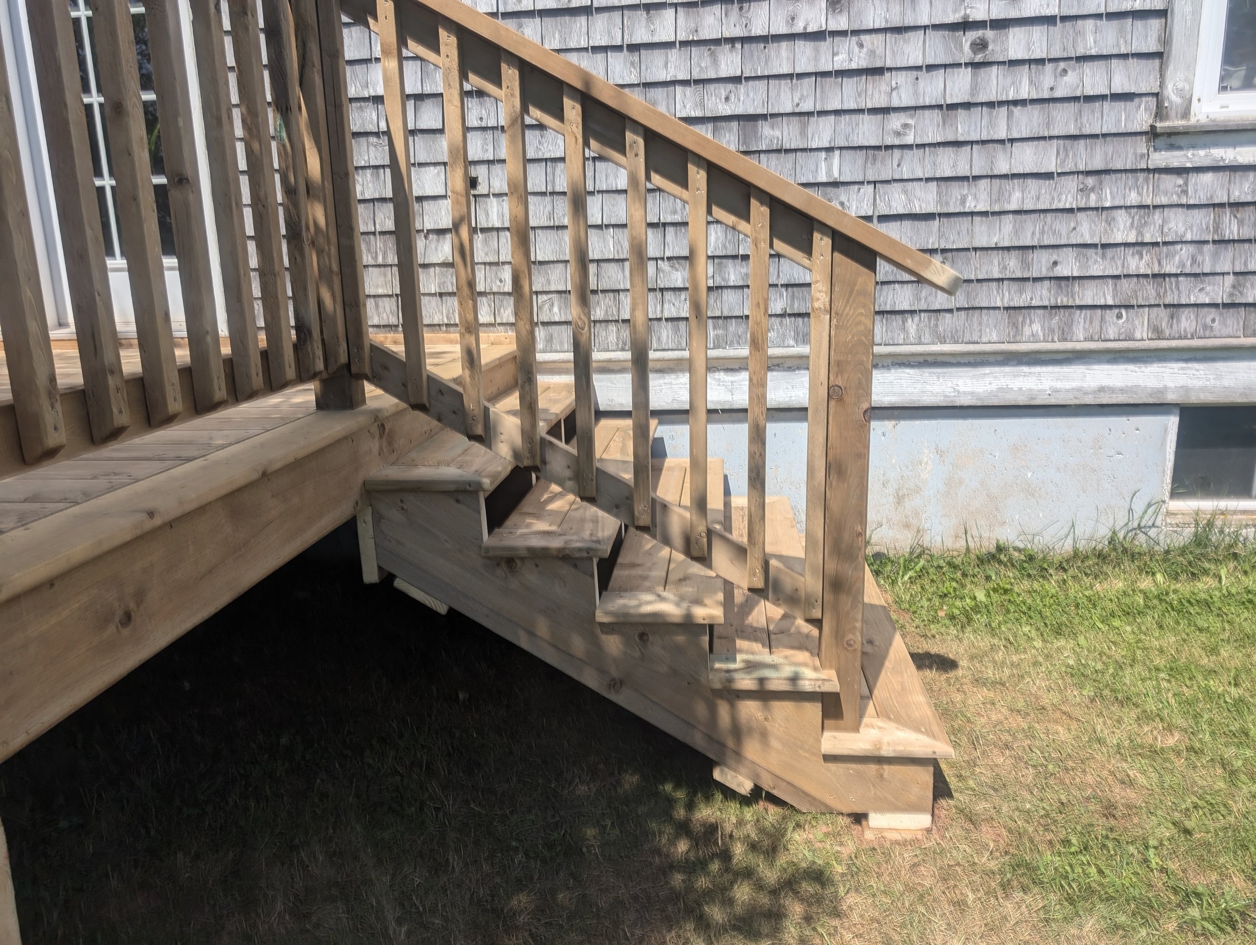 Custom design and built, pressure treated, wooden deck with stairs and wood railing built for homeowner in Stanley Bridge, PEI