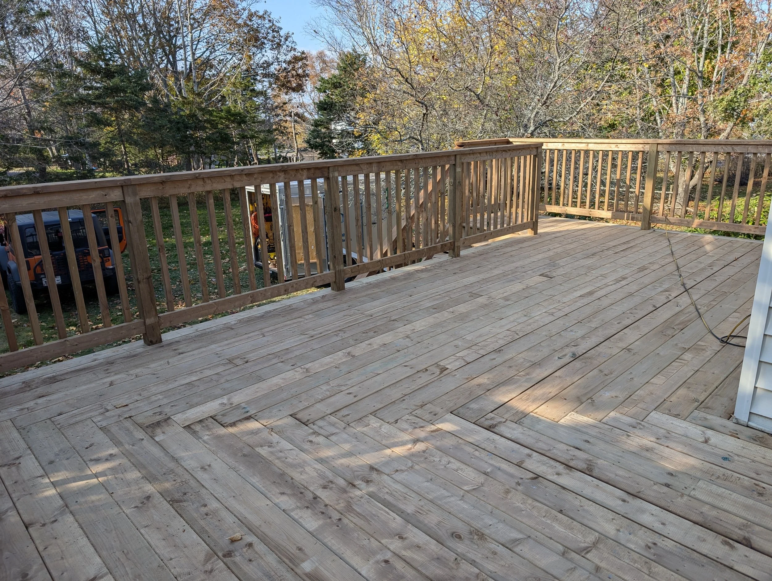 Custom built, pressure treated, upper-level wooden deck with wood railings, and stairs built for a homeowner in Stratford, PEI