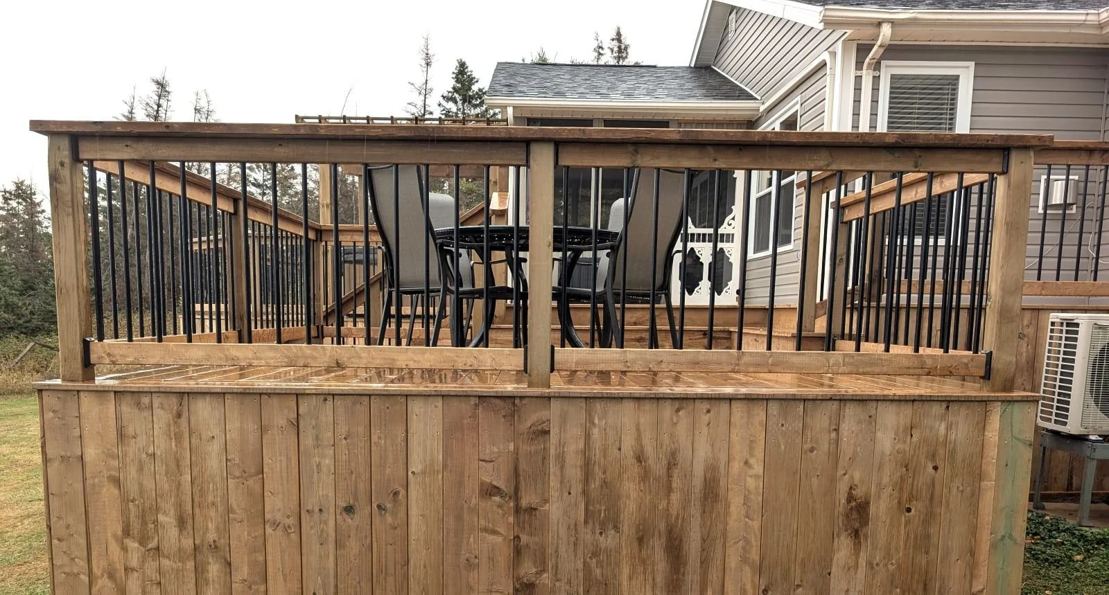 Custom designed and built pressure treated wood and black aluminum railings on multi level deck built for home owner in West Covehead, PEI.