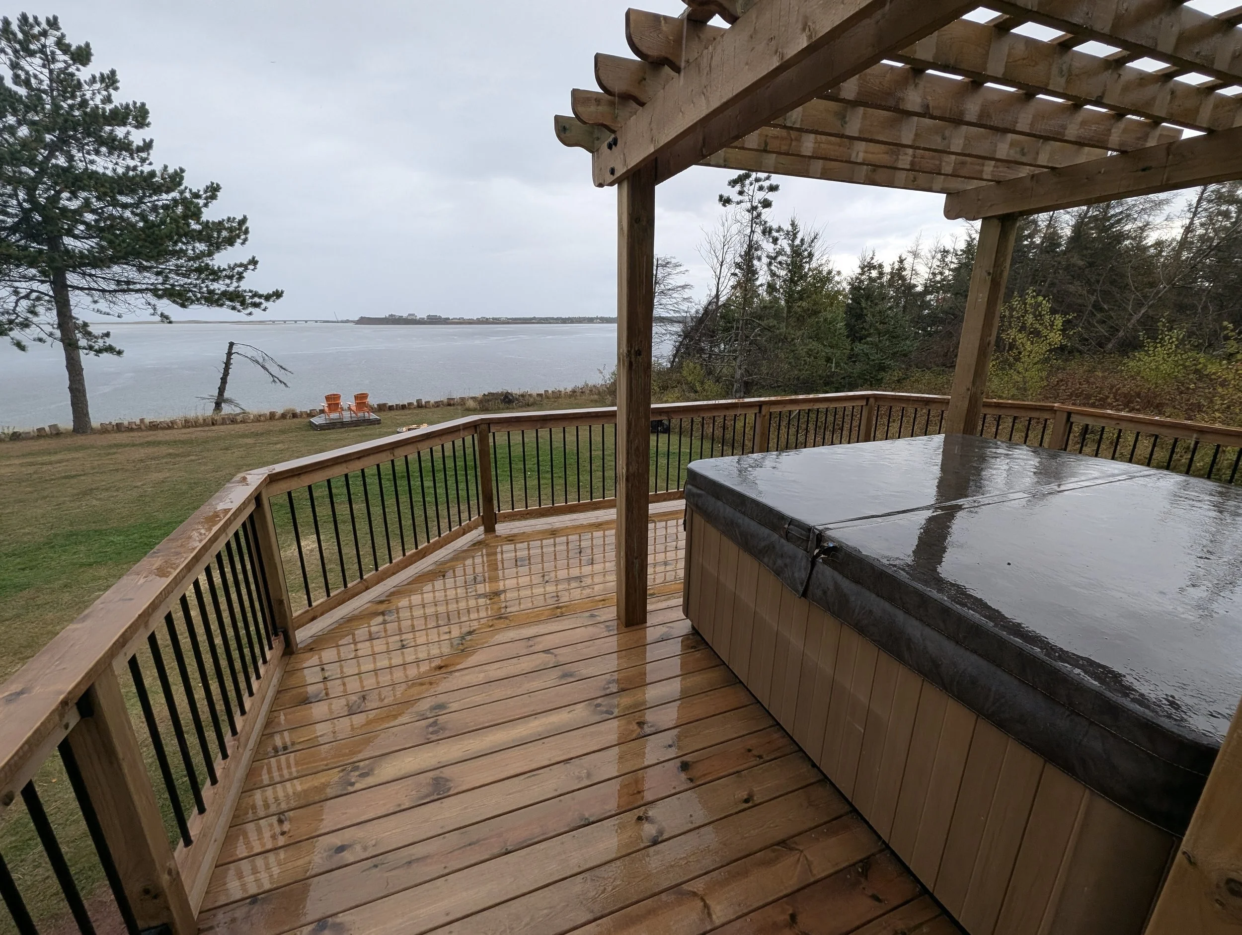 Custom design pressure treated wood pergola on multi-level deck with black aluminum railings and stairs built for a homeowner in West Covehead, PEI 