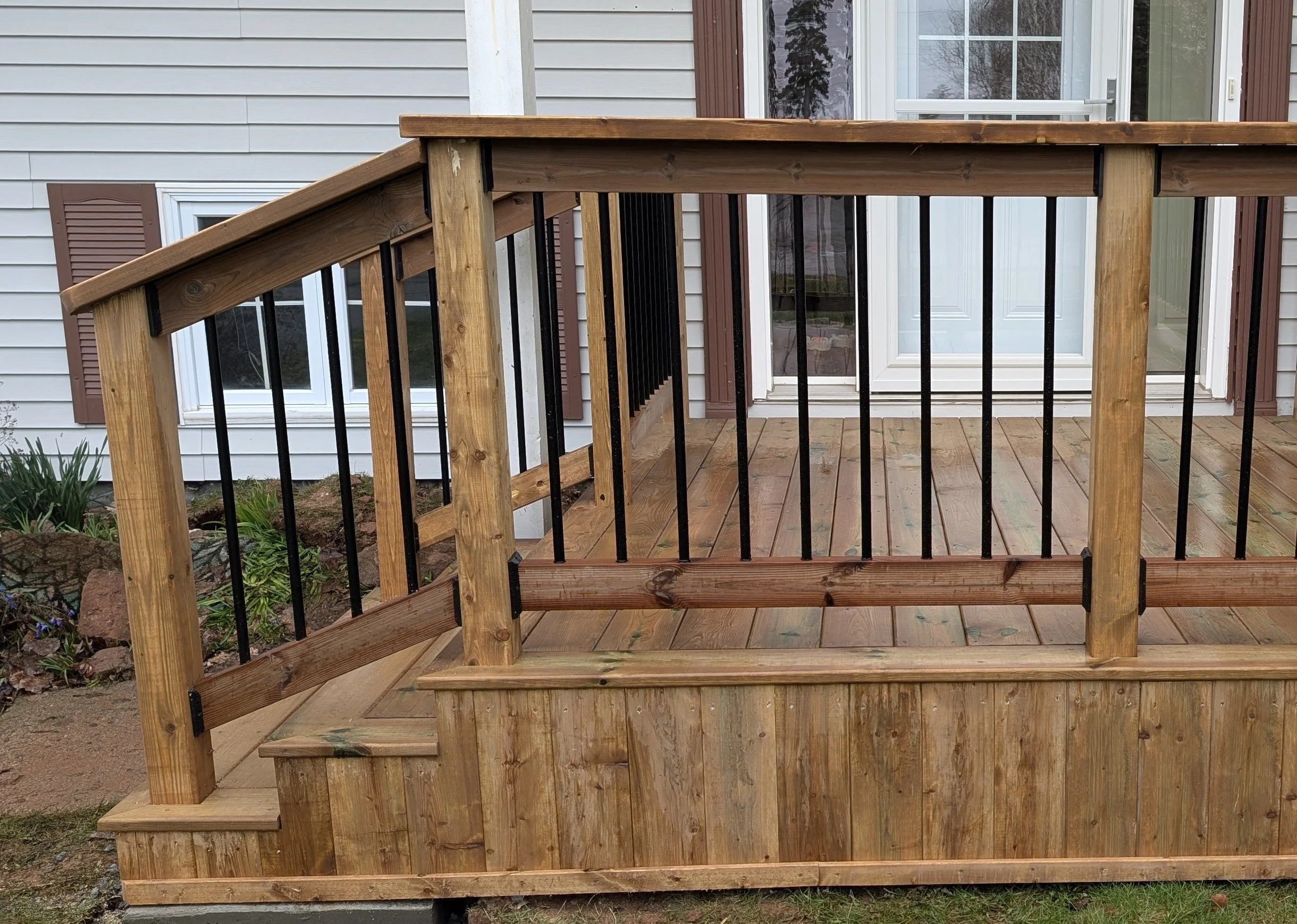 Custom design and built, pressure treated wooden, doorstep with stairs and black aluminum railing built for homeowner in Charlottetown, PEI