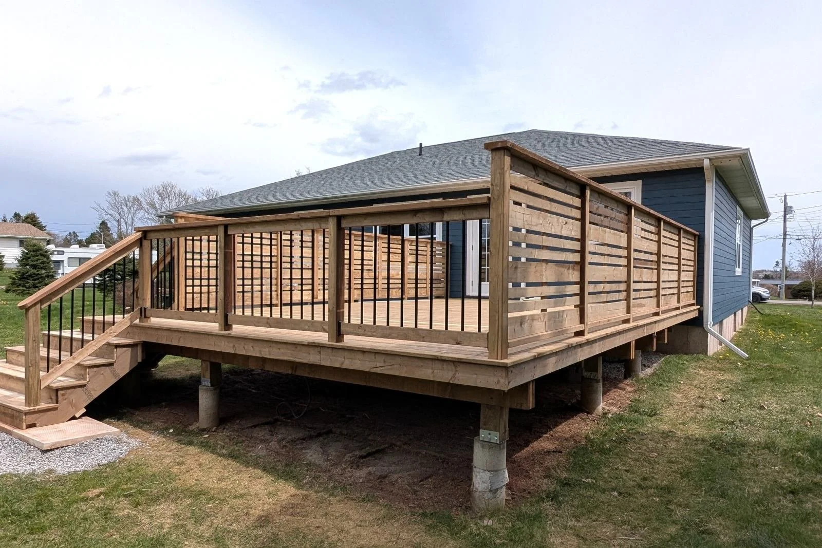 Custom designed and built pressure treated wood and black aluminum railings on deck built for home owner in Winsloe, PEI.