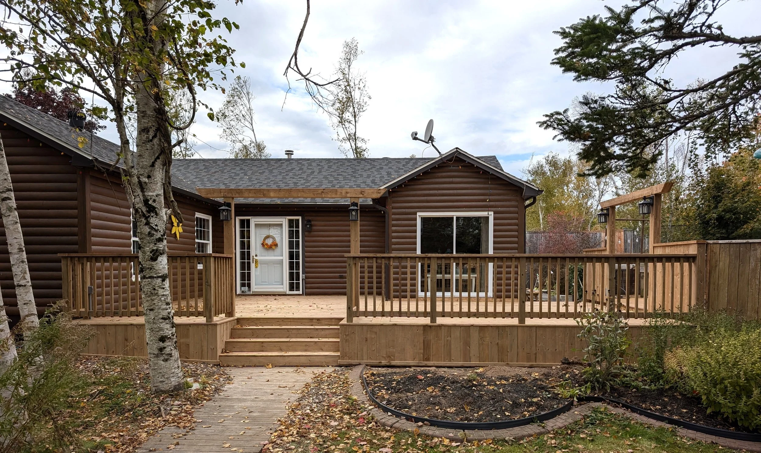 Custom built, pressure treated, multi-level wooden deck with wood railings, and inset step, built for a homeowner in Hunter River, PEI.