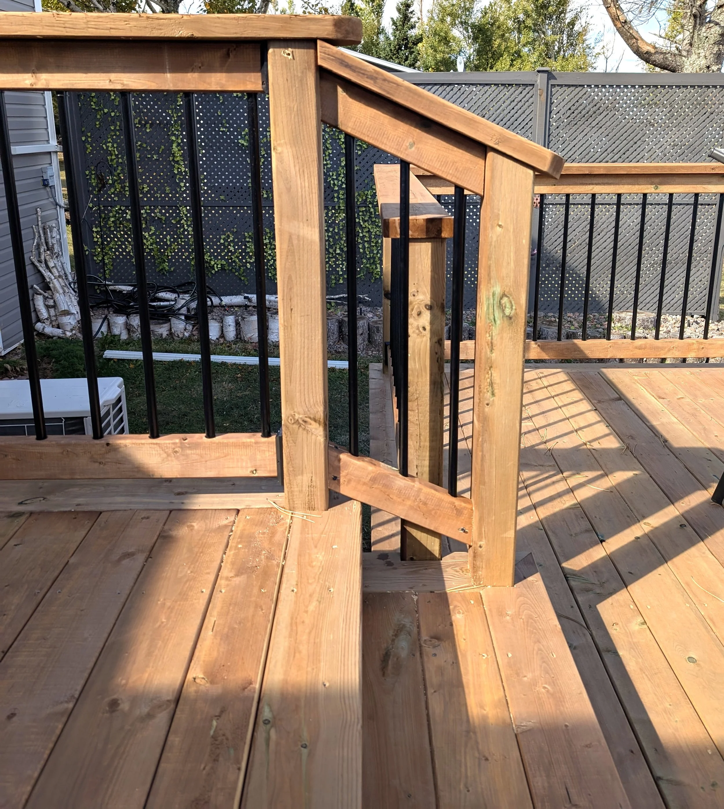 Custom design and built, pressure treated, multi level wooden deck with stairs and black aluminum railing built for homeowner in West Covehead, PEI