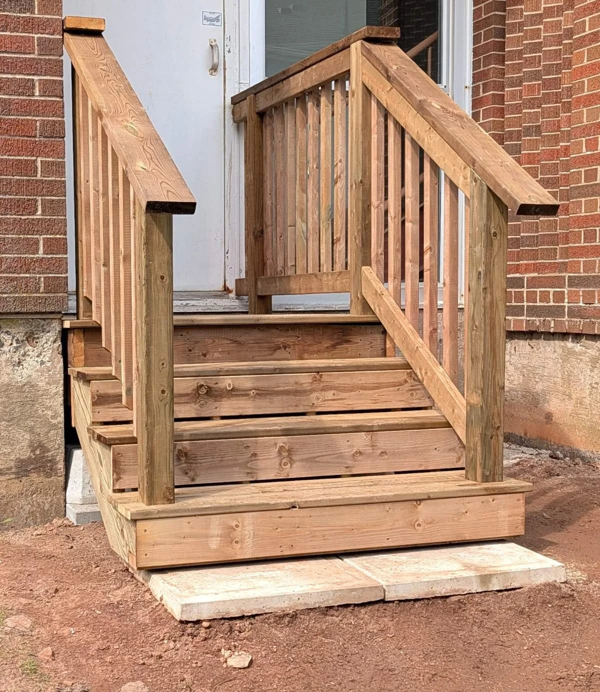 Custom built, pressure treated wooden emergency exit deck with wood railings built for a business owner in Charlottetown, PEI