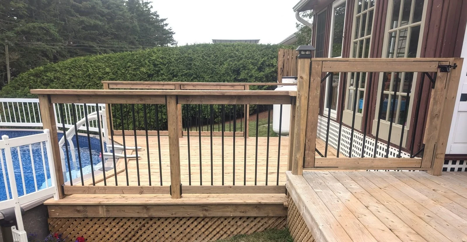 Custom designed and built pressure treated wood and black aluminum railings and gate on pool deck built for home owner in Kensington, PEI.