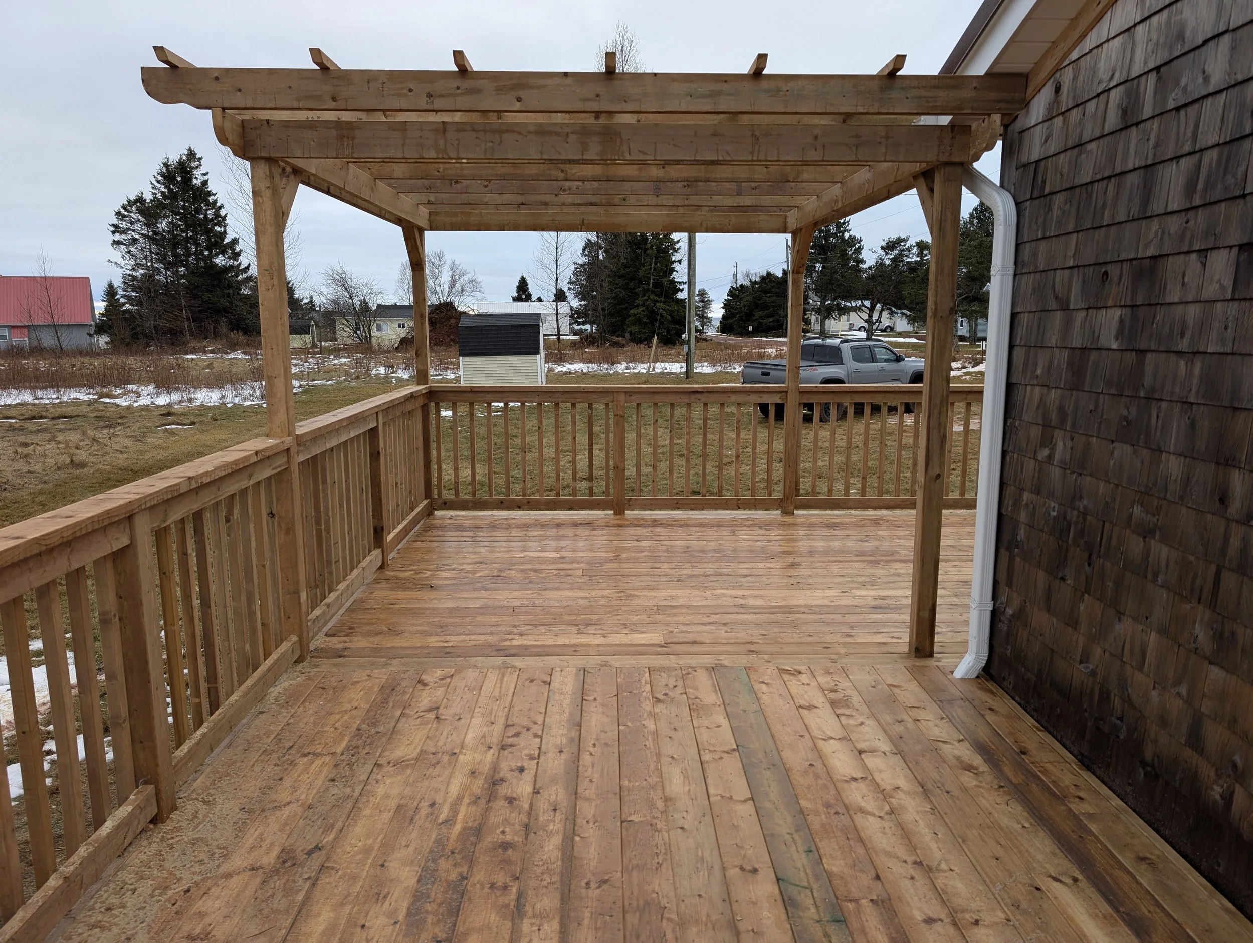Custom pressure treated wooden deck with wood pergola and railings built for a cottage owner in Canoe Cove, PEI