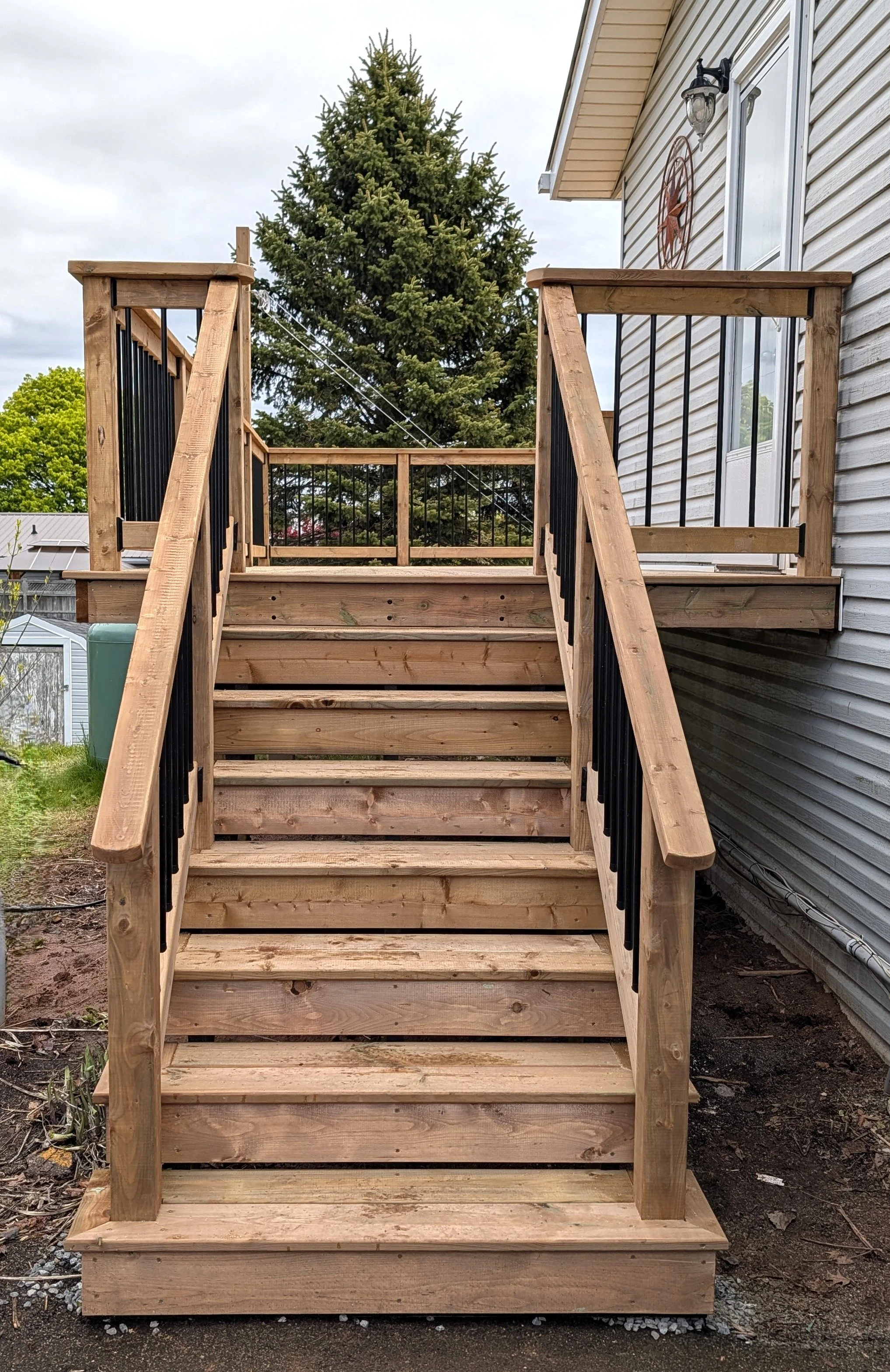 Custom design and built, pressure treated wooden deck with stairs, black aluminum railing  built for homeowner in Charlottetown, PEI