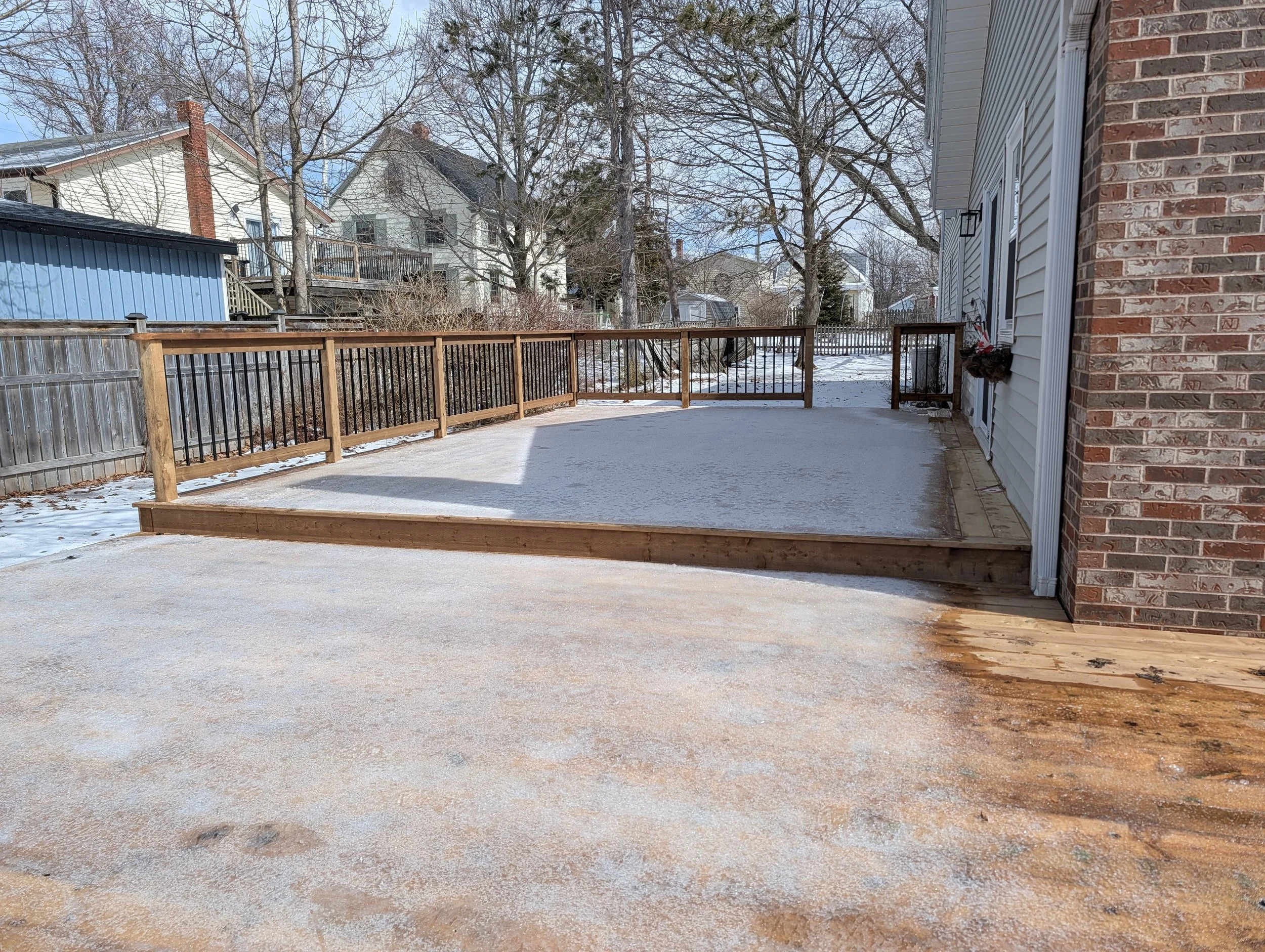 Custom built, pressure treated, ground level wooden deck with wood & black aluminum railings, built in early Spring for a home owner in Charlottetown, PEI.