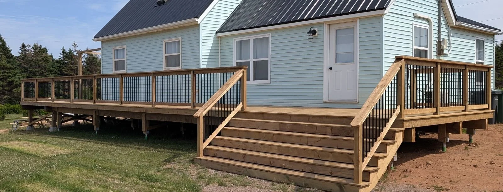 Custom designed and built pressure treated wooden railings on deck built for homeowner in Wild Harbour, PEI.